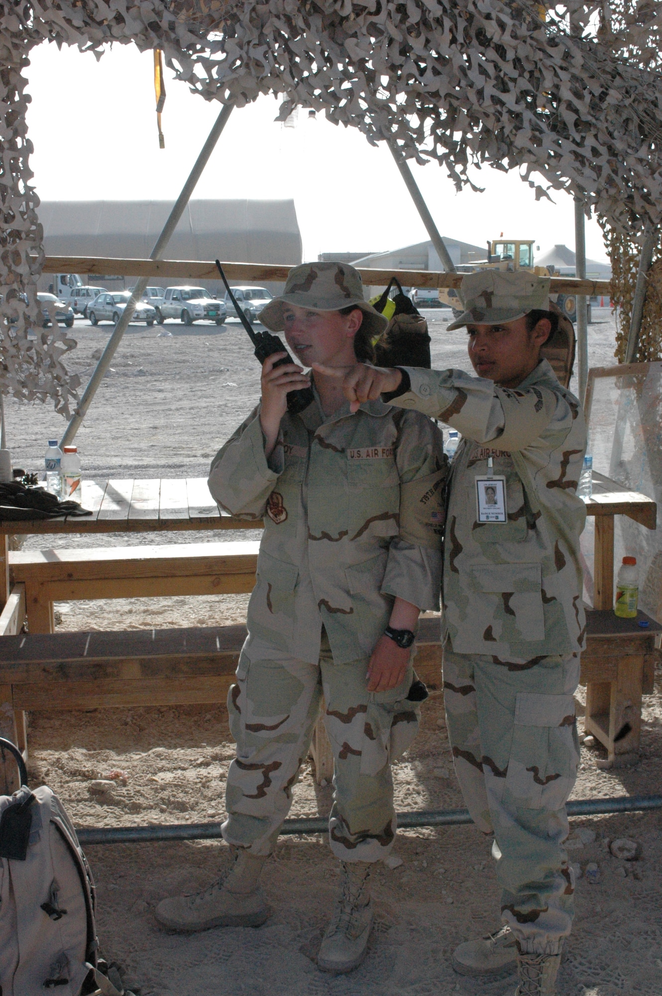 SOUTHWEST ASIA -- Airmen 1st Class Jordan Malfoy and Iris Lopez radio in a head count to the 379th Expeditionary Civil Engineer Squadron escort flight supervisors at a construction site here. The 154 third country national escorts here ensure accountability for every foreign employee on base and provide operational security for the wing. Airman Malfoy is deployed from Eglin Air Force Base, Fla., and Airman Lopez is from Dyess Air Force Base, Texas. (U.S. Air Force photo/Senior Airman Carolyn Viss)