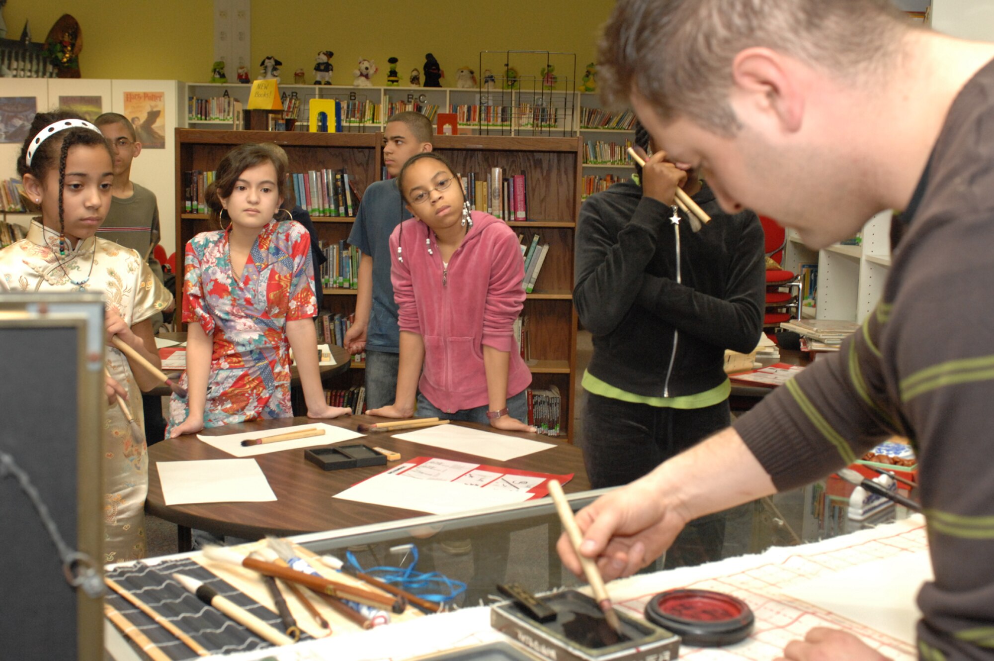 SPANGDAHLEM AIR BASE, Germany -- Students watch closely as Senior Airman Vito Cipolla, 52nd Medical Group pharmacy, dips a brush in black ink as he demonstrates calligraphy to students at Spangdahlem Middle School Feb. 27, 2008. The students had the opportunity to learn calligraphy during the school’s A Day in Ancient China. (U.S. Air Force photo/Airman 1st Class Jenifer Calhoun)