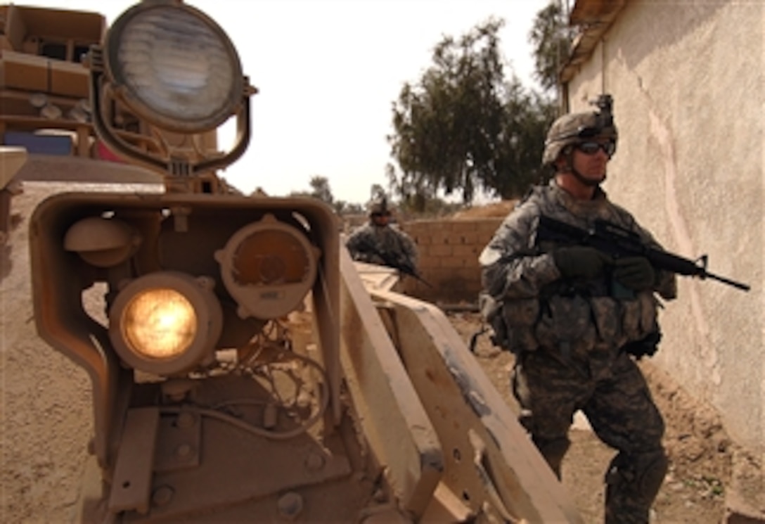 U.S. Army Capt. Shawn Thompson patrols past a Bradley fighting vehicle during a clearing operation in Kesra, Iraq, Feb. 24, 2008.  Thomspon is assigned to the  3rd Infantry Division, 3rd Heavy Brigade Combat Team, 15th Infantry Regiment, 1st Battalion.
