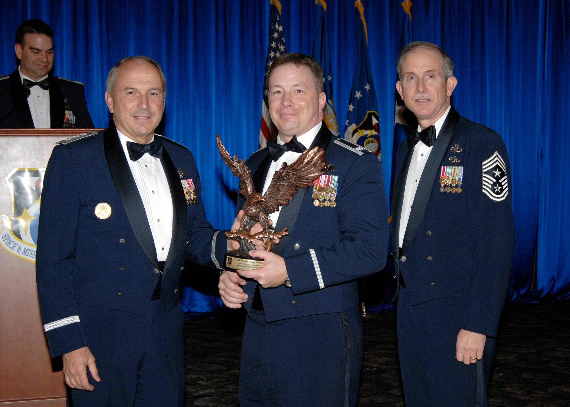 Lt. Col. Brett Scrum accepted the Noncommissioned Officer of the Year Staff Award on behalf of Staff Sgt Dreamy Peckhem, who is currently deployed. Also pictured is SMC Commander Lt. Gen.  Michael Hamel and SMC Command Chief Master Sergeant Steven Crocker. (Photo by Lou Hernandez)