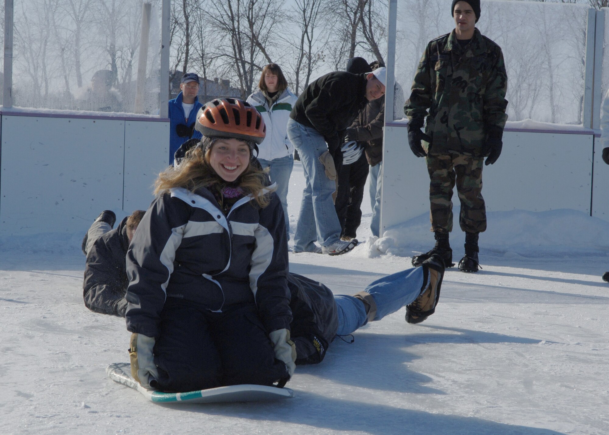 Captain Patrick Kelly and 1st Lieutenant Colby Arends, both 319th Communications Squadron, give 2nd Lieutenant Christine Williams a push during the Winter Bash?s human curling event on the ice rink. The teams were composed of three people and were judged by which team was able to push their person on the sled the furthest. (U.S. Air Force photo/Senior Airman Tiffany Colburn)



