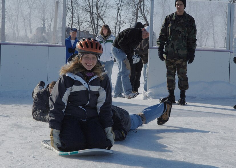 Captain Patrick Kelly and 1st Lieutenant Colby Arends, both 319th Communications Squadron, give 2nd Lieutenant Christine Williams a push during the Winter Bash?s human curling event on the ice rink. The teams were composed of three people and were judged by which team was able to push their person on the sled the furthest. (U.S. Air Force photo/Senior Airman Tiffany Colburn)