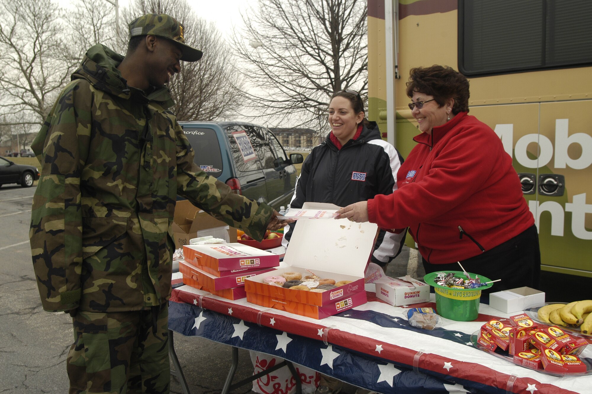 Lisa Stagg, United Service Organization volunteer, hands a sugar donut to Airman 1st Class Jayson Bradley, 436th Aerial Port Squadron, while Leigh Edmonds, USO programs and event manager for the mobile Eastern region provides assistance. The mobile canteen visited the base Feb. 26 and 27 to support Team Dover. (U.S. Air Force photo/ Airman 1st Class Shen-Chia Chu)