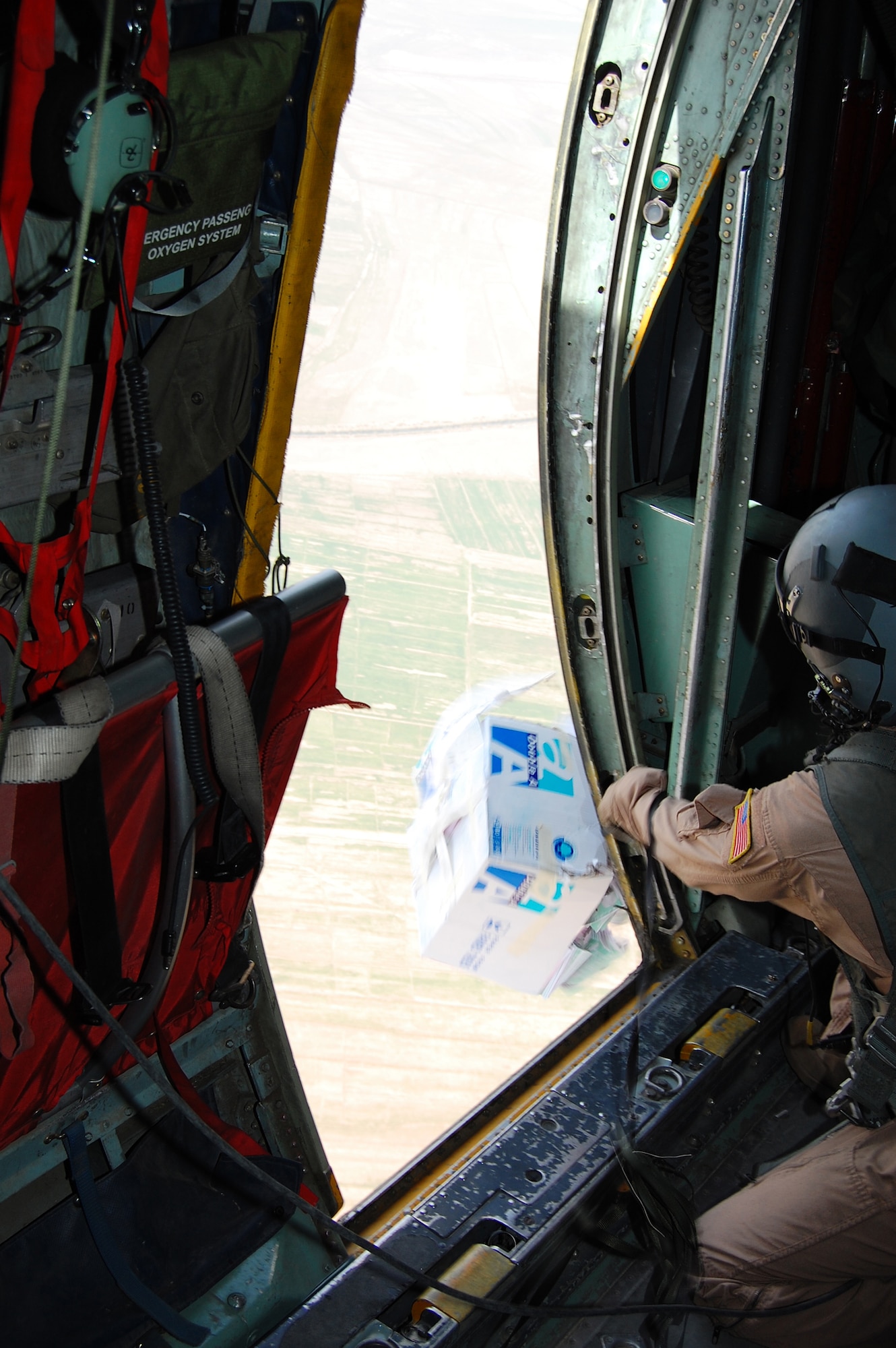 SOUTHWEST ASIA -- Staff Sgt. John Columbia, a loadmaster with the 737th Expeditionary Airlift Squadron, pushes out a container full of leaflets through the troop passenger door of a C-130 Hercules while flying over an Iraqi province recently. The mission is part of leaflet air drop mission supporting the Australians from Overwatch Battle Group [West]-4 in southern Iraq. Sergeant Columbia is deployed from Ramstein Air Base, Germany, in support of Operations Enduring and Iraqi Freedom. (U.S. Air Force photo/1st Lt. Brock Burkhardt)