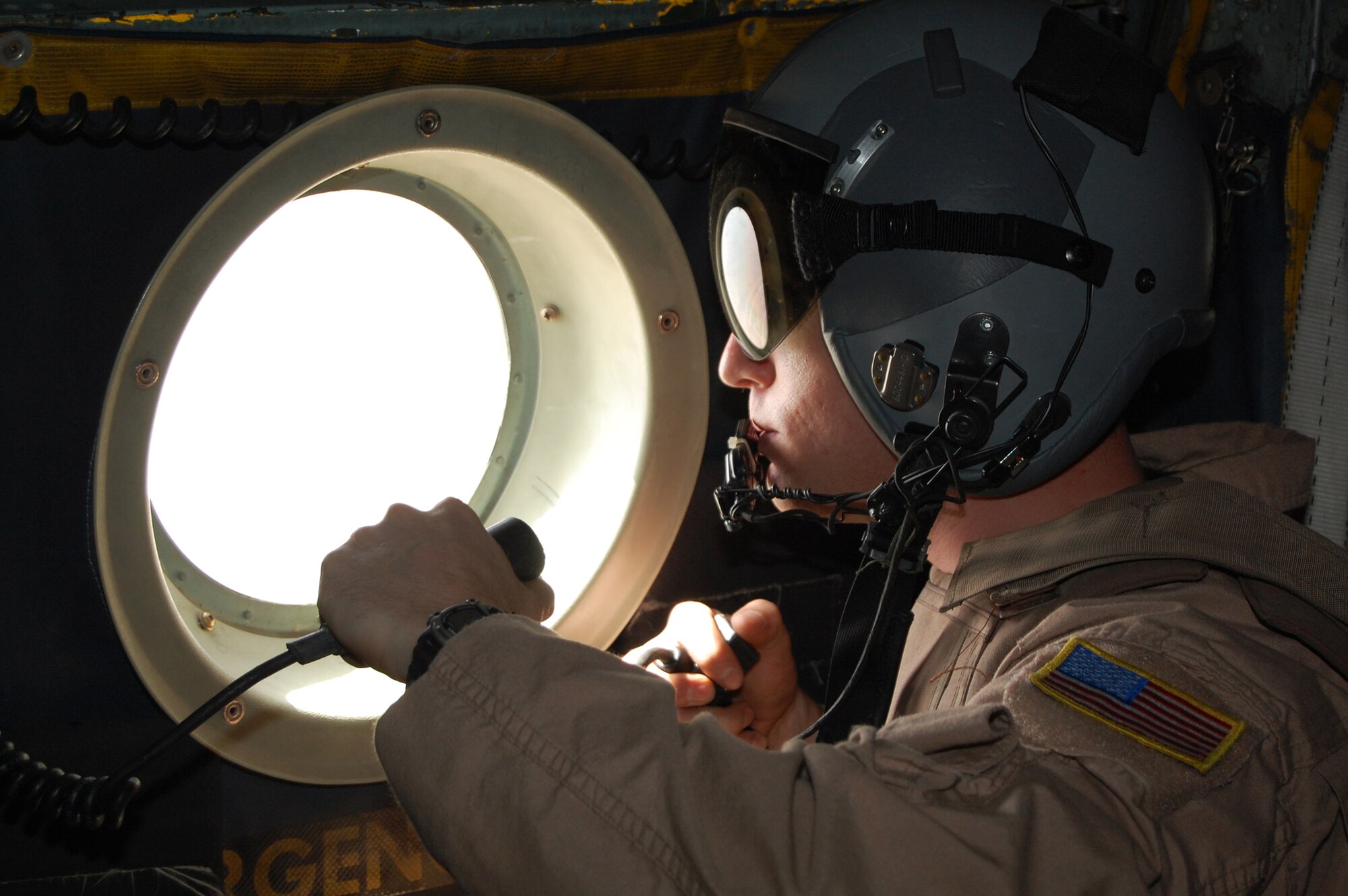 SOUTHWEST ASIA -- Staff Sgt. John Columbia, a loadmaster with the 737th Expeditionary Airlift Squadron, sits in the ready position at a troop passenger door of a C-130 Hercules during a recent mission over an Iraqi province. Sergeant Columbia sits ready to manually dispense chaff/flare if primary means do not function automatically when fired upon. The mission is part of leaflet air drop mission supporting the Australians from Overwatch Battle Group [West]-4 in southern Iraq. Sergeant Columbia is deployed from Ramstein Air Base, Germany, in support of Operations Enduring and Iraqi Freedom. (U.S. Air Force photo/1st Lt. Brock Burkhardt)