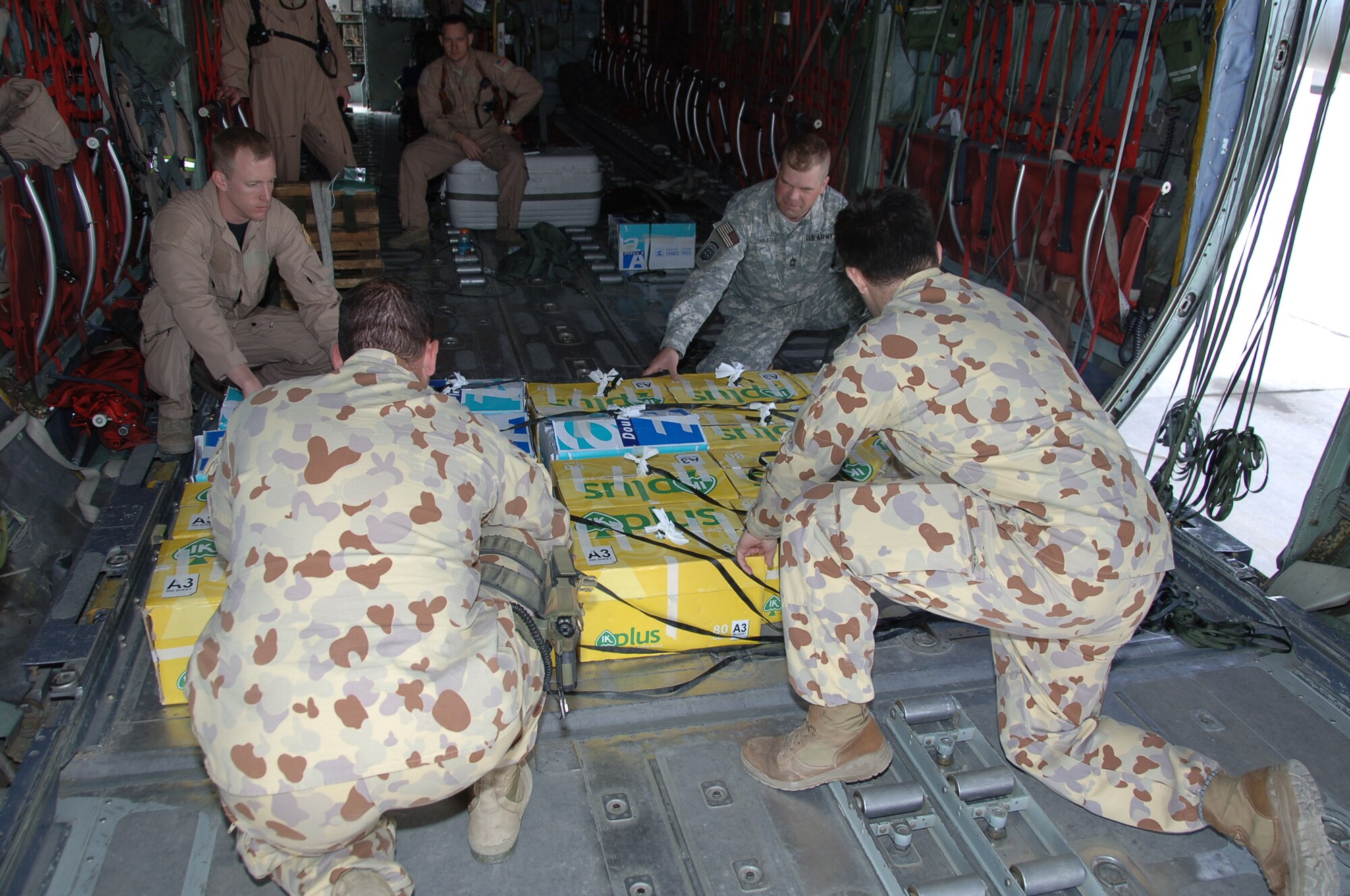ALI BASE, Iraq - Staff Sgt. John Columbia, a C-130 loadmaster from the 737th Expeditionary Airlift Squadron, Master Sgt. John Zimmer, 1st/82nd Airborne and two Australian soldiers load a pallet of leaflets on-board an Air Force C-130 from the 386th Air Expeditionary Wing for a recent air drop. The leaflets were dropped over southern Iraq in Support of Operation Iraqi Freedom. (U.S. Air Force photo/Senior Master Sgt. Miguel Espinoza)