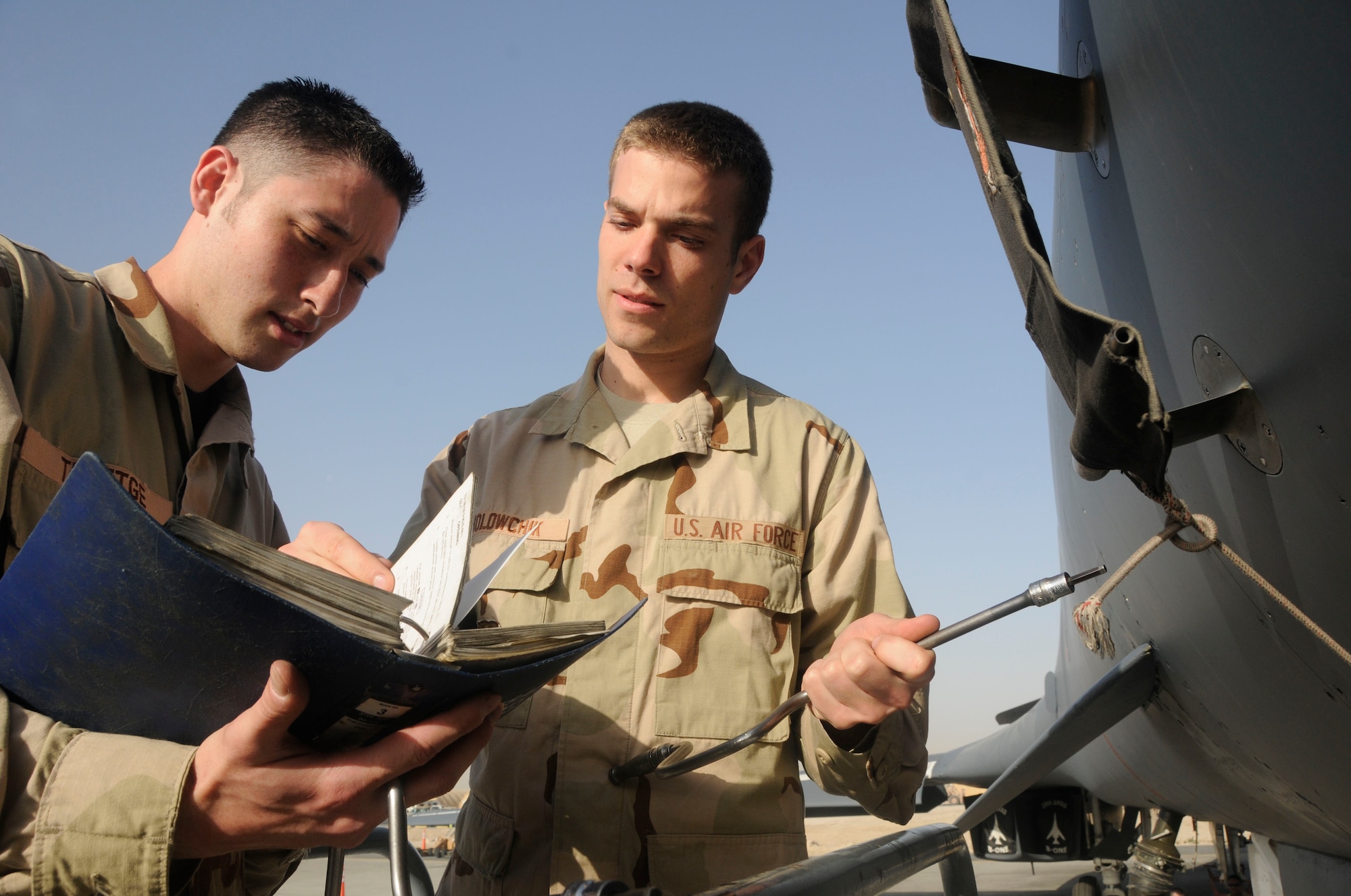 (From left to right) Staff Sgts. Shawn Theetge and John Holowchik go through proper procedures for opening a panel on a deployed B-1 Feb. 27. Both are part of the 37th Aircraft Maintenance Unit. (U.S. Air Force photo/ Senior Airman Domonique Simmons)