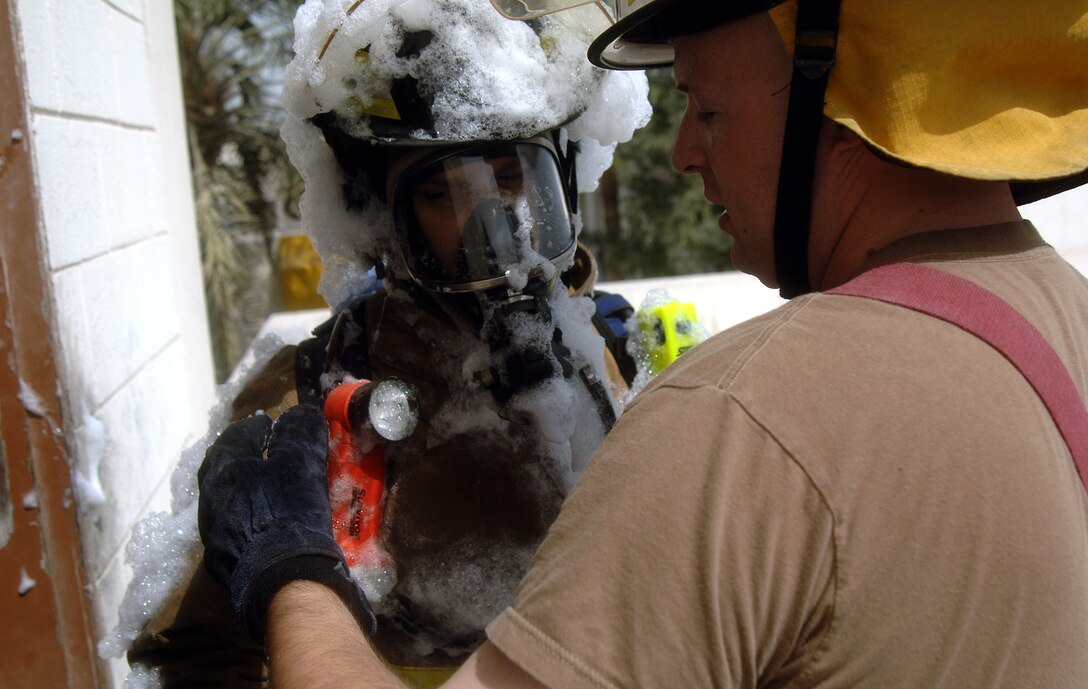 U.S. Navy Petty Officer 1st Class Scott Moore checks the fire-fighting equipment for a fire team member after completing a search and rescue scenario during Exercise Desert Sailor fire brigade training at the Bahrain Civil Defense and Fire School, Feb. 27, 2008. Moore is assigned to the Naval Support Activity Bahrain's Emergency Response Team.