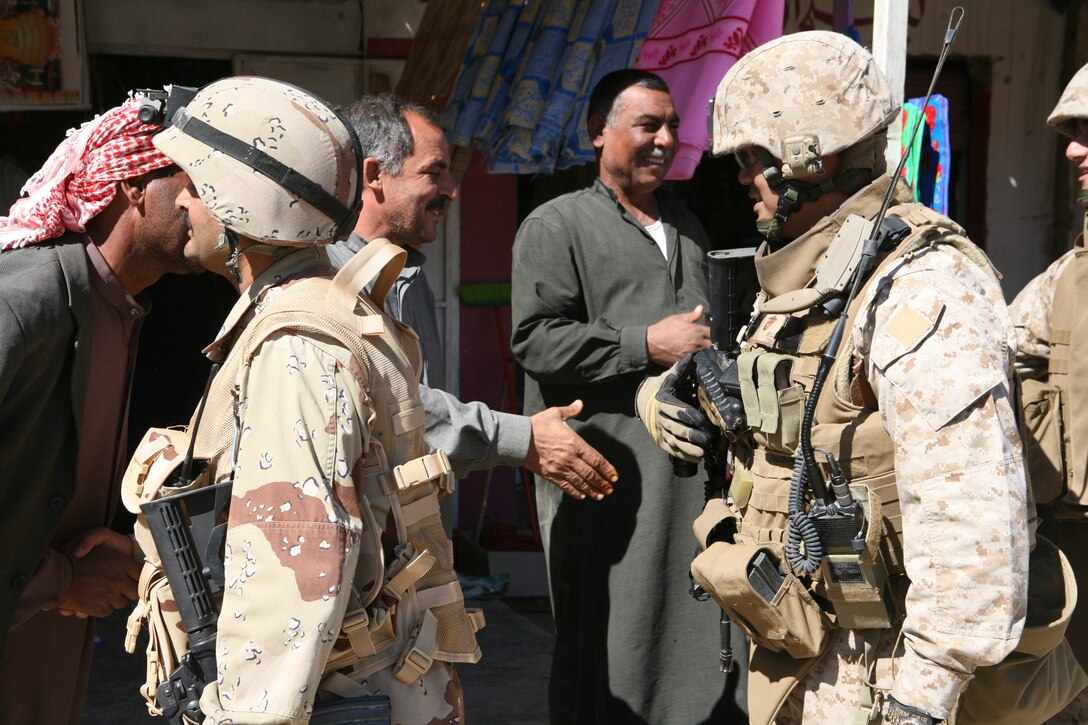 Maj. John E. Orille, (right), 2nd Battalion, 3rd Brigade, 1st Iraqi Army Division Military Transition Team senior adviser, and 1st Lt. Khalid Shihab Ahmed al-Alwani, 2nd Company, 2nd Battalion company commander, greet local men while conducting a presence patrol in the town of Hembis, Iraq.  Al-Alwani uses these patrols as an opportunity to talk to local leaders and members of the Sons of Iraq to gather information on possible enemy activity and build trust with the local population. The 2nd Battalion has been patrolling aggressively in the Diyala River Valley since January in an effort to clear Al Qaeda in Iraq and other terrorist groups from the area.