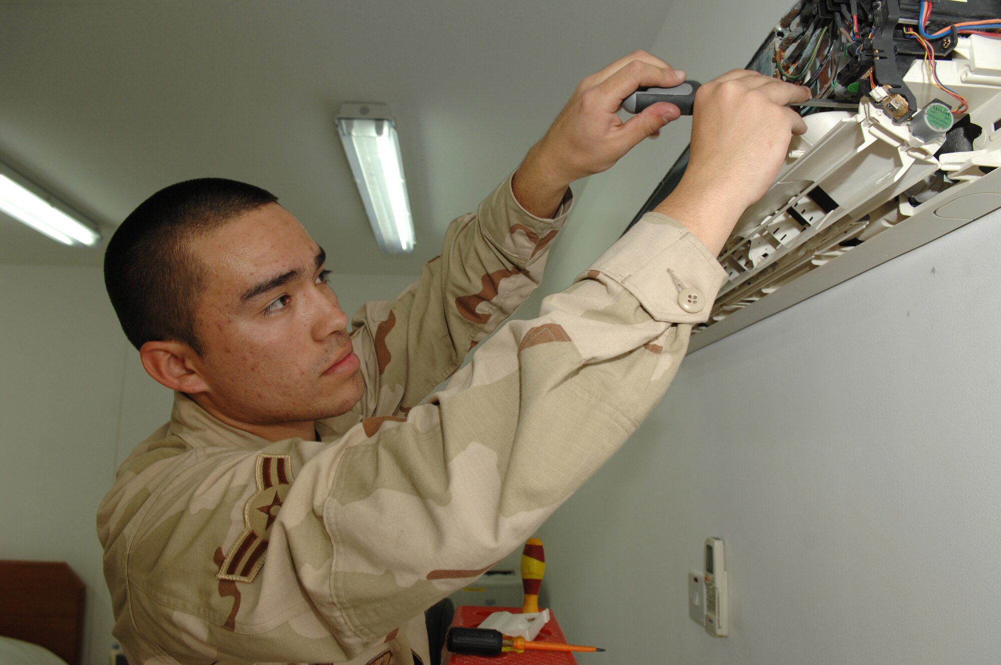 Airman 1st Class Dennis Villegas, 380th Expeditionary Civil Engineer Squadron Heating, Ventilating and Air Conditioning technician, disassembles an air conditioning unit in a 380th Air Expeditionary Wing dormitory in Southwest Asia, Feb. 7. Throughout his life, Airman Villegas has live in Bolivia, Chile, Brazil, the United States of America and is now supporting operations Iraqi and Enduring Freedom in Southwest Asia. He is deployed from McGuire AFB, N.J. (U.S. Air Force photo/Senior Airman Levi Riendeau)