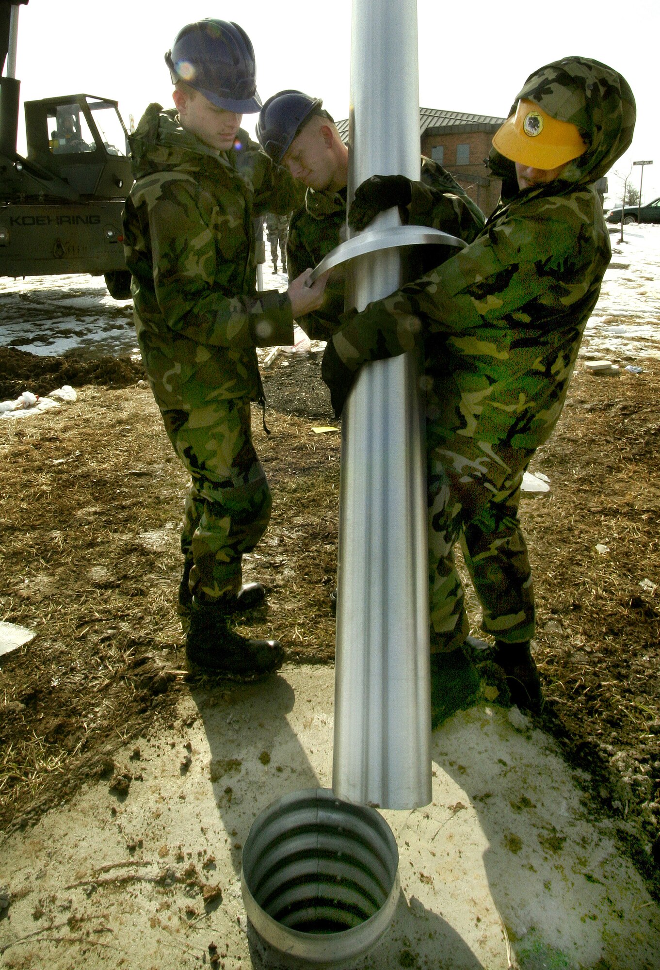 GRISSOM AIR RESERVE BASE, Ind., -- Staff Sgt. Daniel Harshman, left, assists Senior Airmen Matthew Crummel, center, and Wesley Massow, as they place the new flag pole in its base.  The flag pole was installed in March and is located just north of the intersection of Grissom Avenue and Boxcar Street.  A retreat ceremony is performed every day.  Individuals who would like to assist with retreat ceremonies are encouraged to contact the Seasoning Training Program Office. (U.S. Air Force Photo/Tech. Sgt. Patrick M. Kuminecz)
