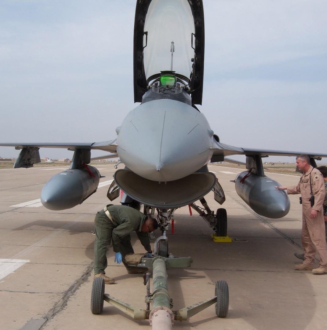 KIRKUK REGIONAL AIR BASE, Iraq -- An F-16 pilot conducts a pre-flight check as 506th Air Expeditionary Group commander Col. Timothy Strawther looks on during a barrier engagement test Feb. 28 here. The barrier engagement tests the Mobile Aircraft Arresting System, which is designed to reduce the forward energy of a fighter aircraft during an emergency landing. 

The MAAS consists of twin platforms connecting a cable that runs across the runway. During an emergency landing, a fighter pilot can drop a hook that latches onto the MAAS cable. The connection reduces the forward energy of the fighter aircraft which cushions impact. Though no fighters are assigned to Kirkuk, these aircraft could be diverted here for reasons ranging from bad weather to mechanical problems. The barrier engagement involved efforts from the 506th Expeditionary Operations Support Squadron, Civil Engineer Squadron, Logistics Readiness Squadron, Security Forces Squadron and Communication Squadron. The two F-16s that participated in the engagement were from the 421st Expeditionary Fighter Squadron. (U.S. Air Force photo by Maj. Stephen Miceli)
