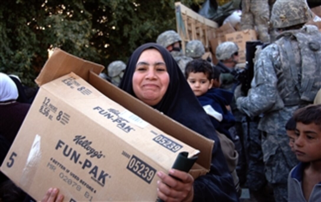 A local Iraqi woman smiles as she carries her humanitarian aid box in Qadasiyah, Iraq, Feb. 21, 2008. 