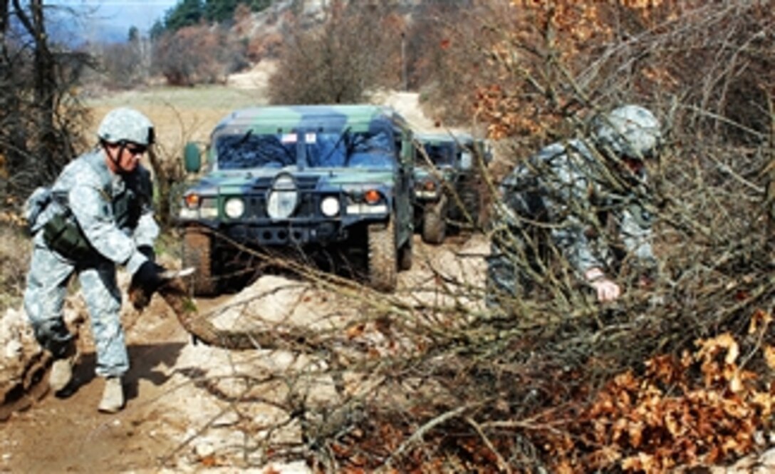 U.S. Army Staff Sgt. Larry Dean and Spc. Tony Weatherman help clear the road for vehicles enroute to one of the guard posts between the Kosovo and Serbian borders, March 4, 2008. Dean and Weatherman are assigned to Battery A, 1st Battalion, 194 Field Artillery Regiment.