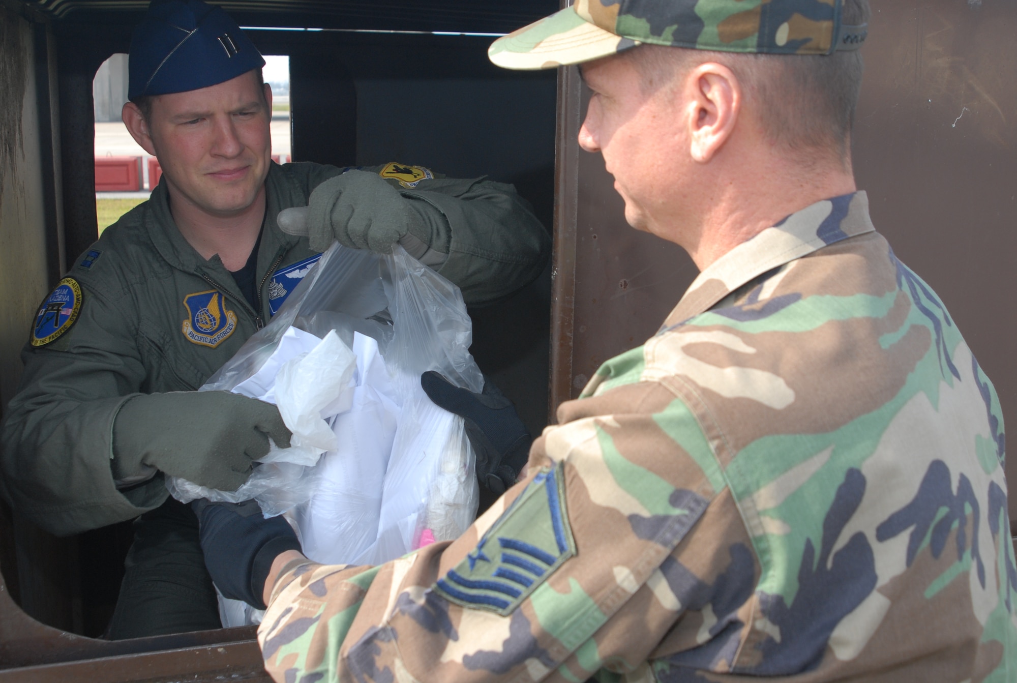 Capt. Jeffrey Schrum and Master Sgt. Kenneth Horn, 18th Wing operational security office check through a wing unit's dumpster, looking for OPSEC material that might have been thrown out.  Members of the OPSEC office make random trips around base, ensuring all the units of the 18th Wing are adhering to proper OPSEC practices.  (U.S. Air Force photo/Staff Sgt. Christopher Marasky)