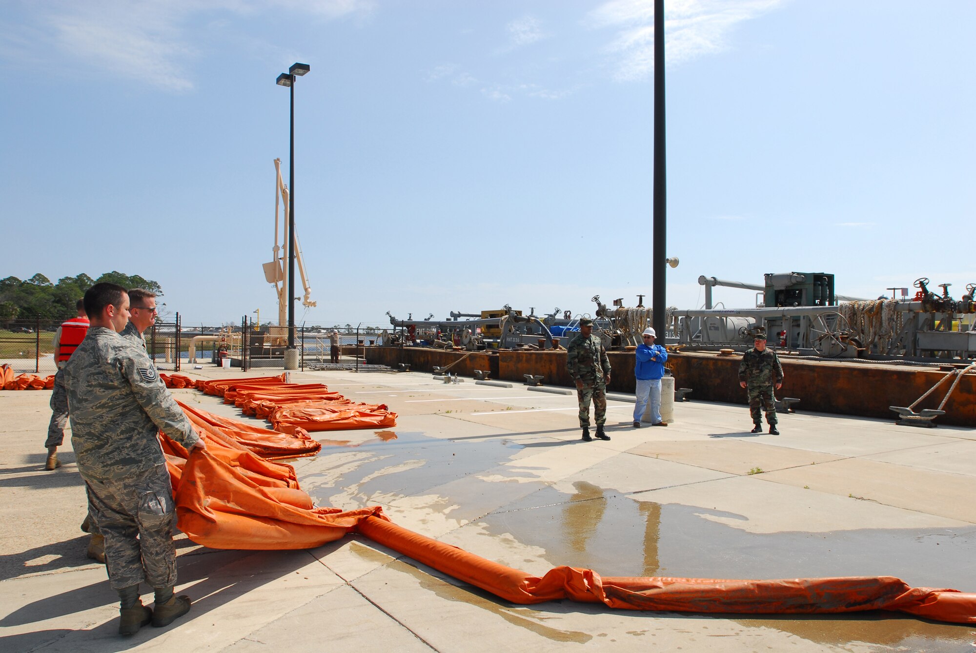 Tech. Sgt. Shawn Fligg (front), 1st Special Operations Logistics Readiness Squadron, drags segments of a protective boom around the fuel pier on Hurlburt Field March 6. In case of a fuel leak the boom would contain the spill preventing damage to protected wetlands along the Santa Rosa Sound. The newly constructed, $5.3 million fuel pier accepted its first barge March 6. The fuel pier pumps fuel to Hurlburt Field through an underground pipe, which will greatly increase the efficiency of delivering fuel to the base. The old fuel pier was destroyed during Hurricane Ivan in September 2004. (U.S. Air Force photo/Airman 1st Class Jason Epley)