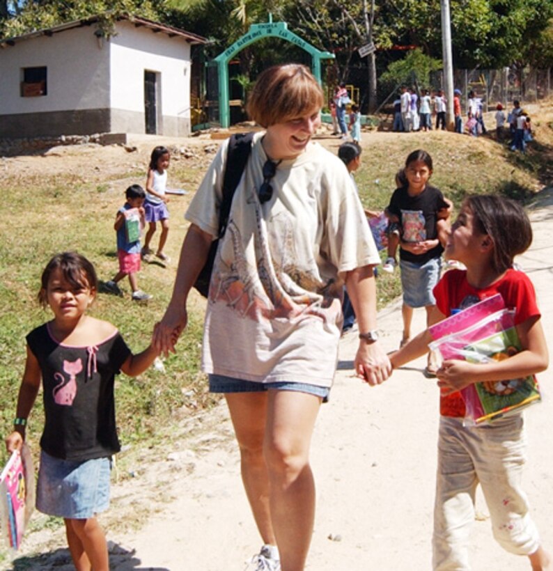 SOTO CANO AIR BASE, Honduras--Joined by her two new friends, Major Regina Paden moves down the road to the next element of Project Beautiful, an effort to enhance the Capiro community, a rural community surrounding Comayagua, Honduras, Feb. 23. Major Padden was one of more than two dozen Joint Task Force-Bravo volunteers and 20 Honduran Boy Scouts who planted mango, mandarin and Nancy trees, provided school supplies for 100 students and teachers and collected 500 pounds of roadside trash.  (U.S. Air Force photo by Tech. Sgt. Jennifer Wilson)                      