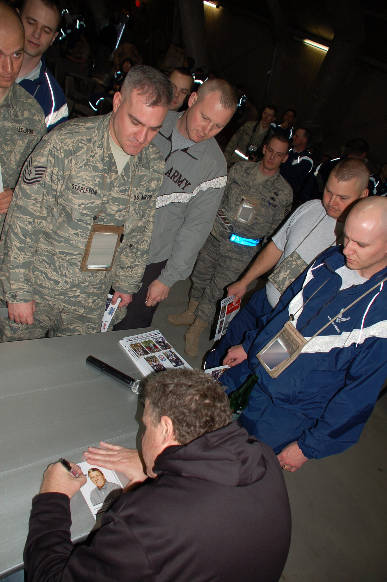 Sports Illustrated writer Peter King signs autographs for Airmen March 4 at the recreation center on Manas Air Base, Kyrgyzstan. Mr. King traveled to Kyrgyzstan as part of the United Service Organizations National Football League tour that brought San Diego Chargers Luis Castillo, Chicago Bears Tommie Harris, and Carolina Panthers Mike Rucker to see military members supporting operations in Afghanistan. The visitors spent the day visiting Airmen at their work centers to see firsthand how members of the 376th Air Expeditionary Wing support the war on terrorism. They participated in a question and answer session with the Airmen, Soldiers and Marines transiting the base, hanging around afterward to sign autographs for sports enthusiasts. (U.S. Air Force photo/Lt. Col. Adriane Craig) 
