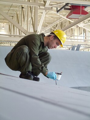 WESTOVER AIR RESERVE BASE, Mass ? TSgt. Christopher W. Davis a Sheet Metal Specialist in the Isochronal (ISO)Dock, works on replacing a damaged section of a C-5?s wing while below three Airman from the 445th Airlift Wing, Wright-Patterson Air Force Base, Ohio work on securing the sheet metal section from the inside of the wing. The Ohio Airman are here for a few weeks for training on the C-5 airframe by the Westover maintainers, while their unit makes the conversion from C-141s to the C-5 Galaxy. This is the first C-5 to be put through the rigorous Westover inspection under the new label of Regional ISO Center. 