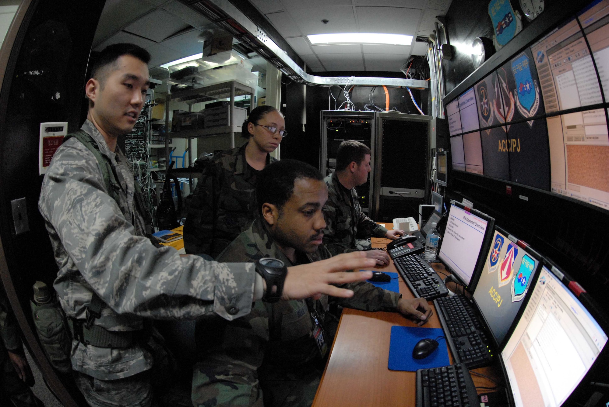 OSAN AIR BASE, Republic of Korea – Maj. Robert J. Bonner, Air Component Command plans and coordination directorate, describes mechanics behind ACC's massive cyber network used to execute air operations during Exercise Key Resolve. Tech. Sgt. Alvin  Mills, (front, sitting),  NCOIC combined battle-watch, manages the daily battle-rhythm, as augmentees Senior Airman Patricia A. Kelly-Schmutz and Senior Airman Andrew Devin learn how to interface information streaming from the Combined Forces Commander in Seoul. (U.S. Air Force photo/Staff Sgt. Lakisha Croley)