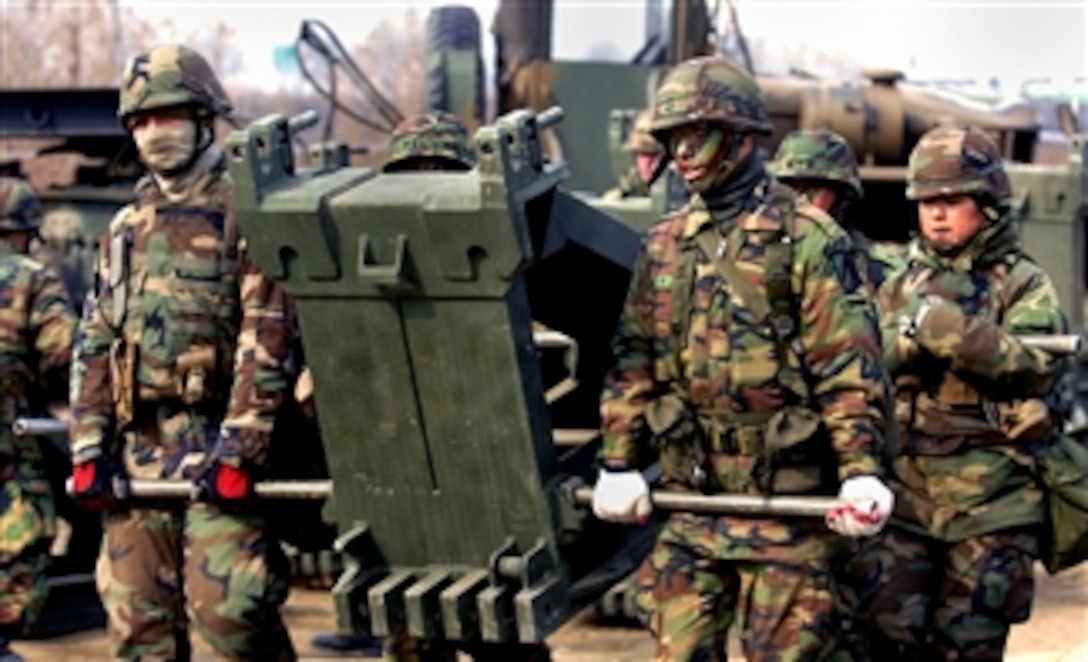 U.S. Navy Seabees and members of a Republic of Korea bridge construction company move a 700-pound transom beam into place during a bridge-building exercise, March 6, 2008. The Seabees are assigned to Naval Mobile Construction Battalion 5. 