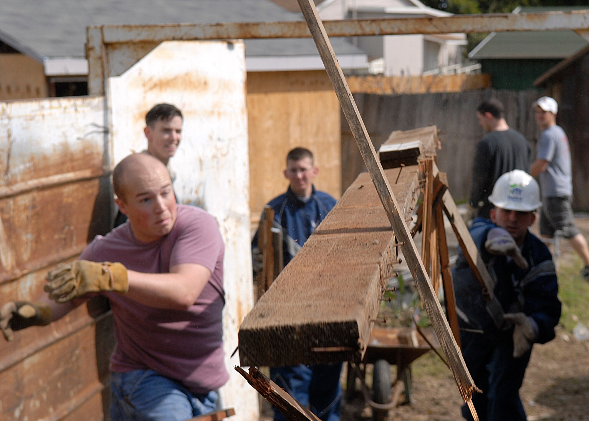 SANTA MARIA, Calif.--  Airmen 1st Class Chad Usher and Airman Basic Kyle Palmer toss a plank of wood into a dumpster on Mar. 1 while volunteering with Habitat for Humanity. Programs like this allow Airmen stationed at Vandenberg AFB to help rebuild homes in the local community.  Habit for Humanity gives Airmen the opportunity to work with local civilians in building a better community.  (U.S. Air Force photo/Airman 1st Class Andrew Satran)
