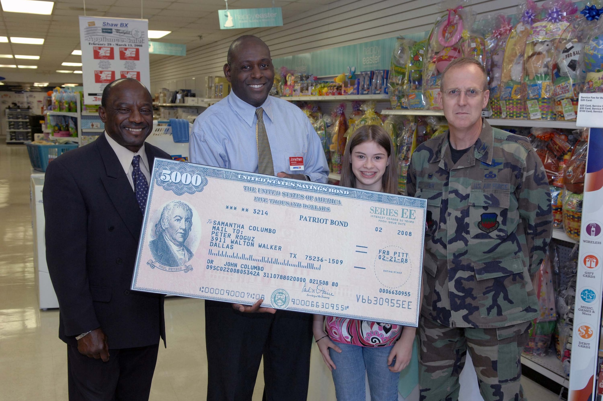 SHAW AIR FORCE BASE, S.C. -- Col. Francis Xavier (right), 20th Mission Support Group commander, Maurice Joiner, base exchange general manager, and Jonathan Bright, BX Manager, present a $5000 U.S. Savings Bond to Samantha Colombo, daughter of Col. John Colombo, 20th Operations Group commander, March 6 at the base exchange. Samantha earned the savings bond by winning first place in the AAFES "You Made the Grade" contest. (U.S. Air Force photo/Airman 1st Class Matthew Davis)