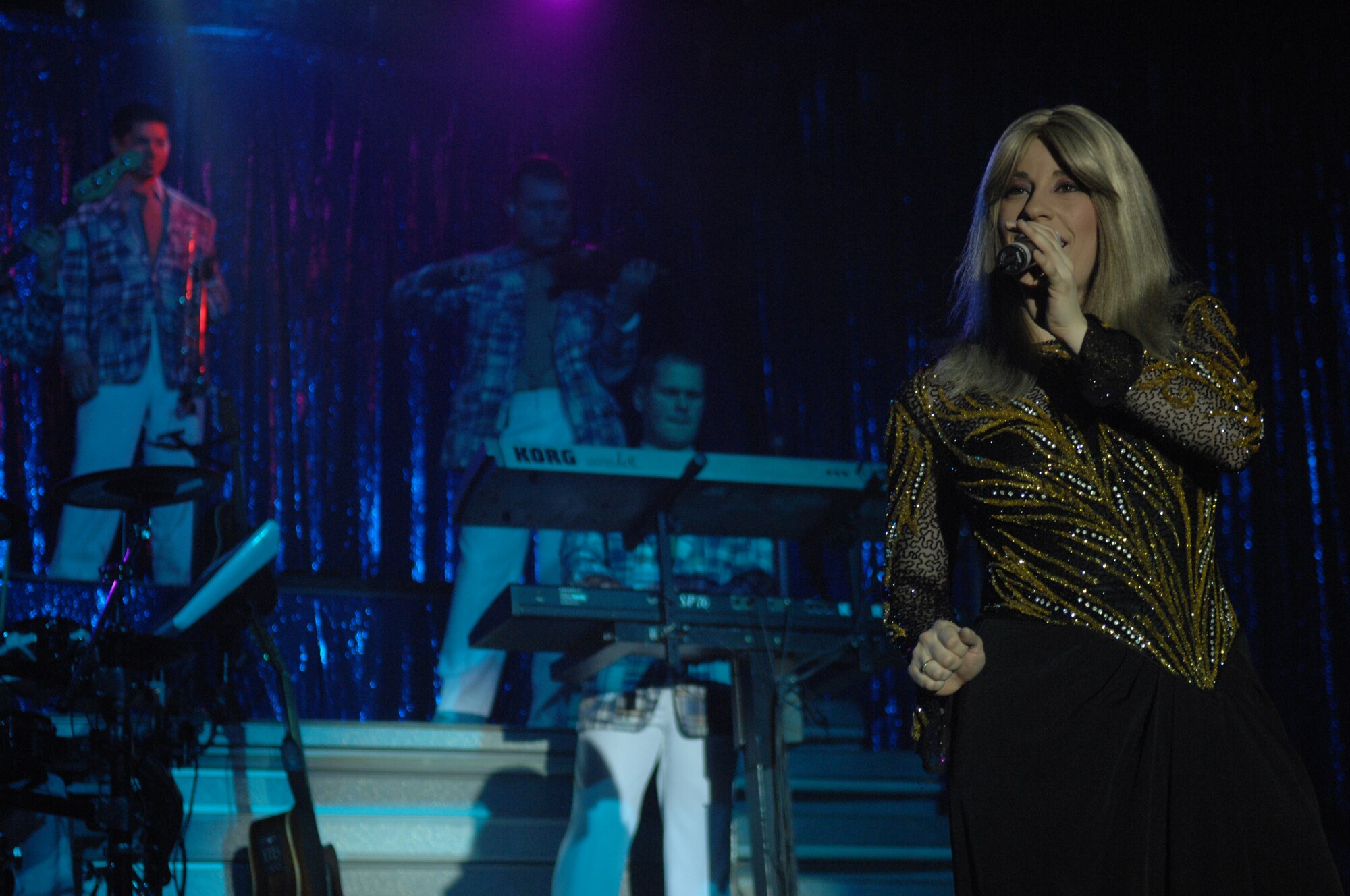 Wearing a blonde wig and shimmering gown, Tops in Blue vocalist 1st Lt. Kimberly Robinson impersonates Barbra Streisand. Impersonations of Chubby Checker, Johnny Cash and Stevie Wonder were also part of the show. (U.S. Air Force photo by Staff Sgt. John Barton)