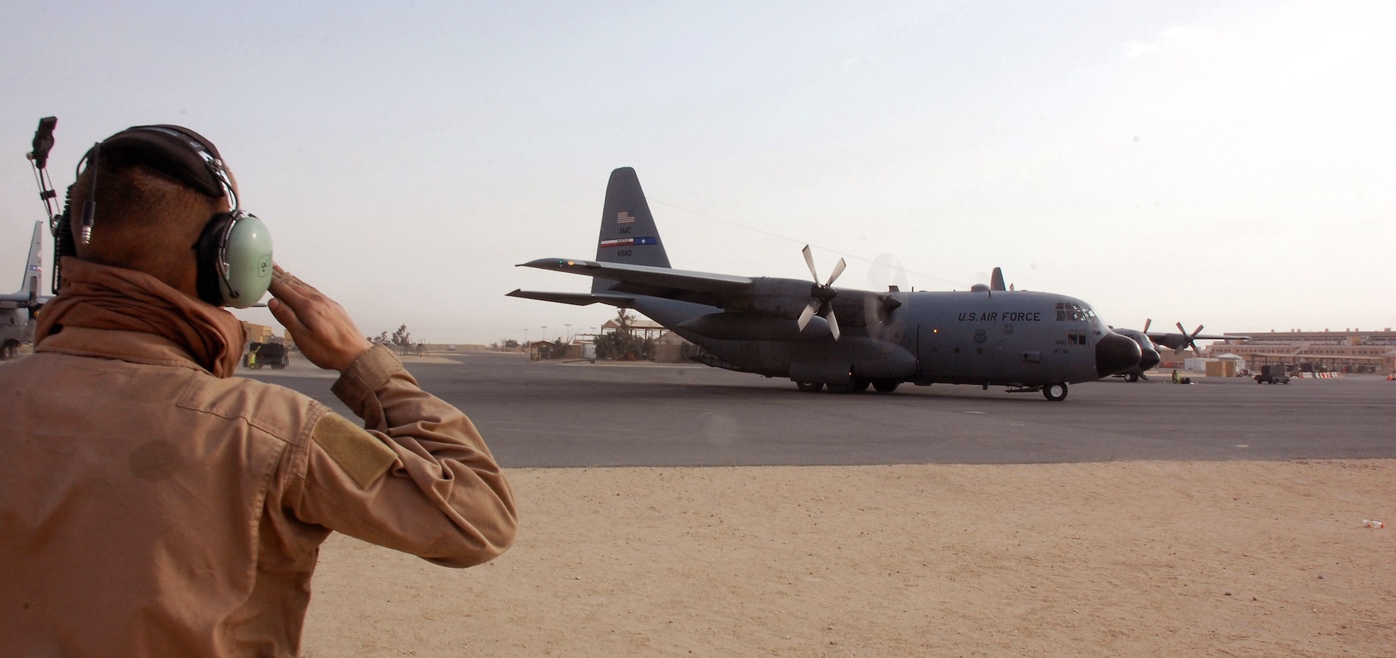 Airman 1st Class Buddy Bewick, 386th Expeditionary Aircraft Maintenance Squadron salutes the aircraft commander of a C-130 Hercules at a Southwest Asia air base. The aircraft is heading for a mission into Iraq for Operation Iraqi Freedom. (U.S. Air Force photo/Tech. Sgt. Michael O'Connor)
