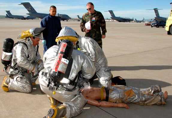 This is just a test: Technical Sgt. Caesar Deleon (in blue coveralls), Fuel Systems Journeyman for the 349th Component Maintenance Squadron, Travis AFB, watches as a fire department rescue team treats a simulated victim his team pulled from a confined space on a KC-10 tanker aircraft. Sergeant Deleon was the runner and equipment monitor for the 349th CMS Fuel Shop during a confined space extraction exercise held March 6 in hangar P-14 for the 349th AMW’s Unit Compliance Inspection. This exercise simulates the procedure used to rescue someone during in-tank maintenance should they become injured or overcome by fuel fumes. Once out of the confined space, the victim is carried out of the area and given appropriate medical care. (U.S. Air Force photo/Master Sgt. Wendy Weidenhamer)