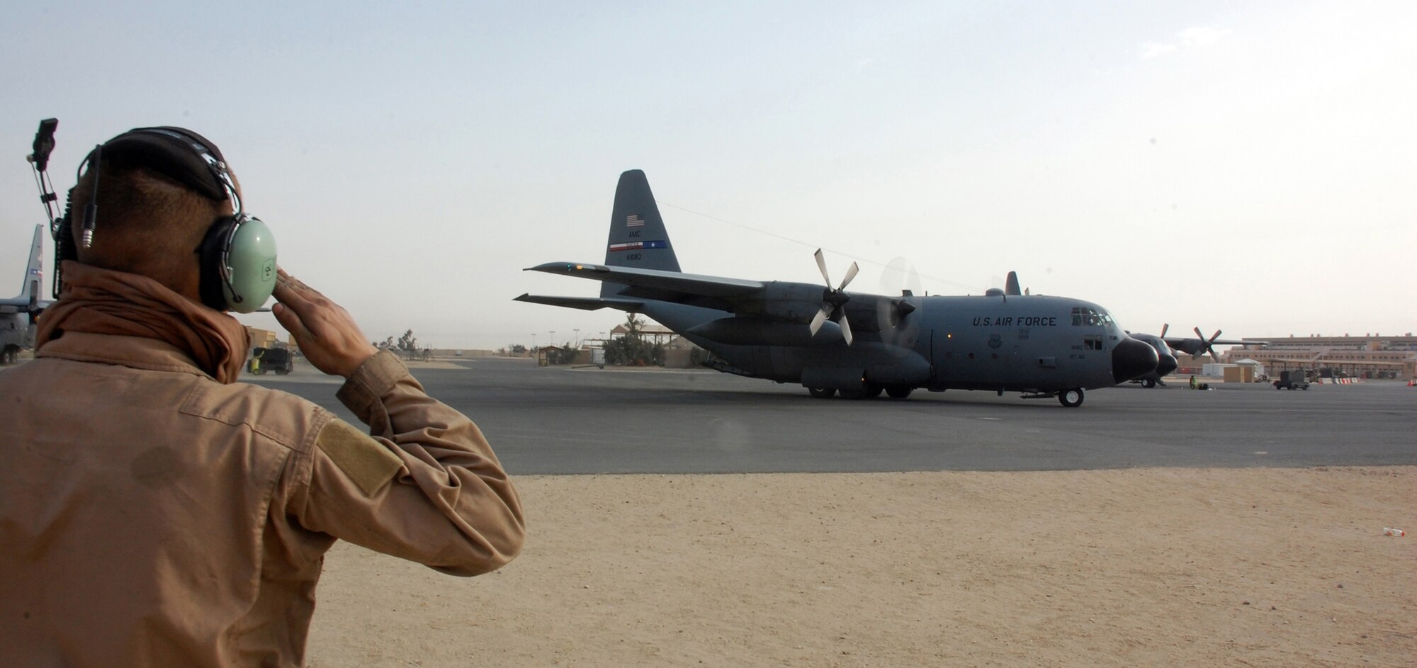 SOUTHWEST ASIA -- Airman 1st Class Buddy Bewick, 386th Expeditionary Aircraft Maintenance Squadron salutes the aircraft commander of a C-130 Hercules at a Southwest Asia air base. The aircraft is heading for a mission into Iraq for Operation Iraqi Freedom. (U.S. Air Force photo by Tech. Sgt. Michael O’Connor)