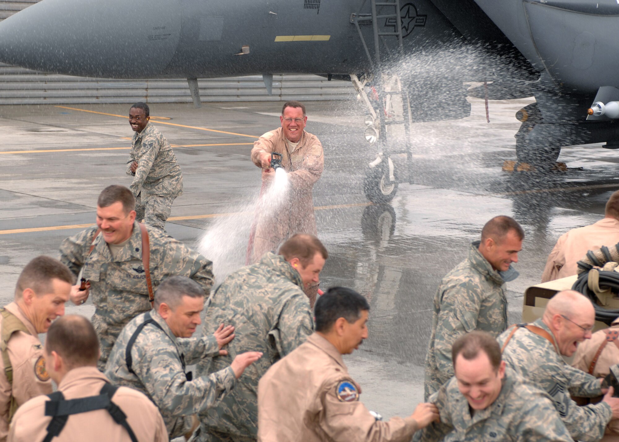 BAGRAM AIR BASE, Afghanistan - Brig. Gen. Bill Hyatt sprays military members of the Bagram community during his fini flight here March 6. General Hyatt secured the hose from a crew chief after he was customarily sprayed with water for his final flight. (U.S. Air Force photo by Master Sgt. Demetrius Lester)