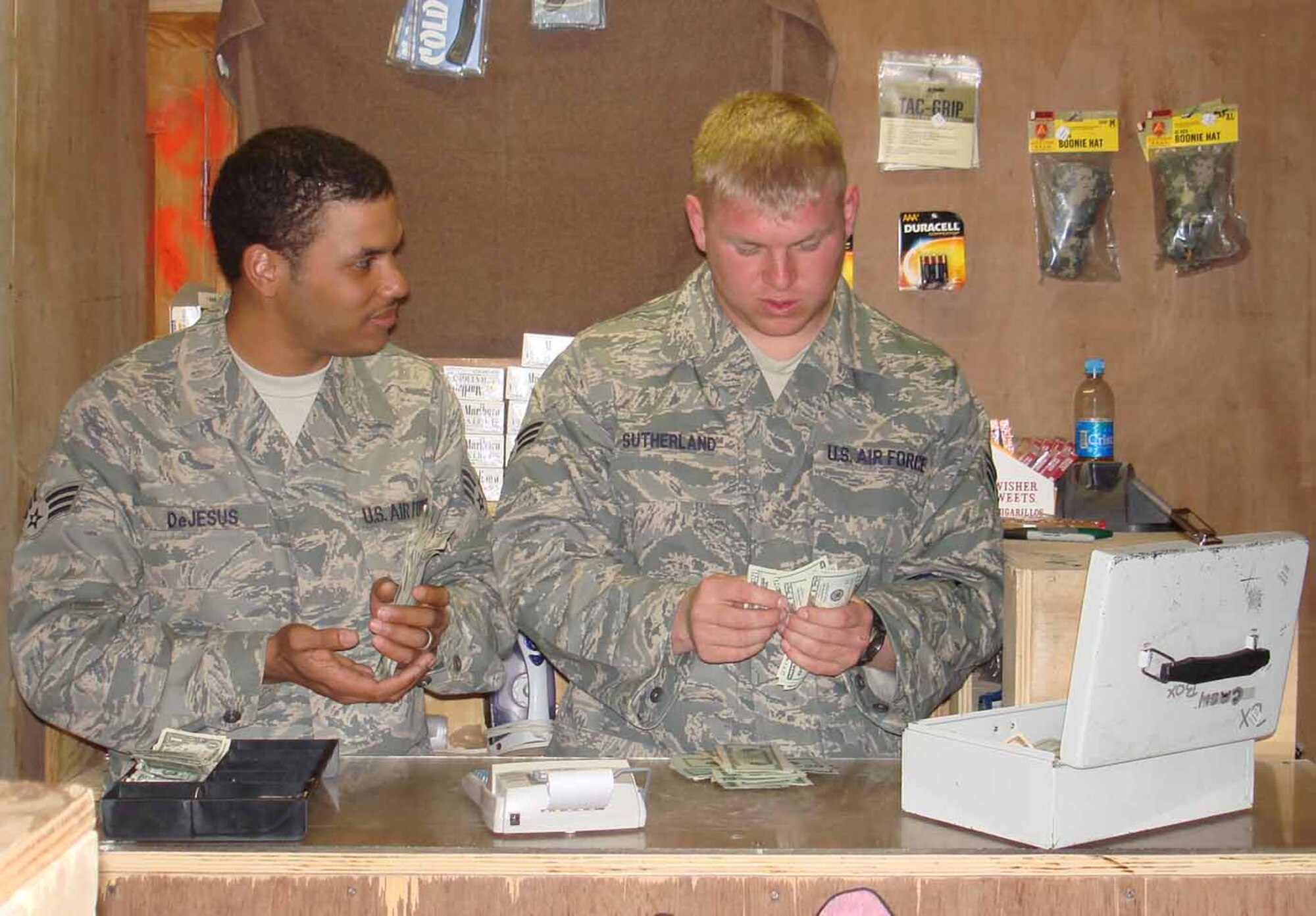 FORWARD OPERATING BASE LAGHMAN, Afghanistan -- Senior Airmen Eliceo DeJesus (left) and David Sutherland (right) count money at the Base Exchange here at the close of business. The Services Airmen are responsible for Morale, Welfare and Recreation activities and operate the BX, fitness center and midnight dinner at the dinning facility for the 550 deployed Soldiers and Airmen assigned here.  (U.S. Air Force photo by Air Force Captain Heather Kekic) 