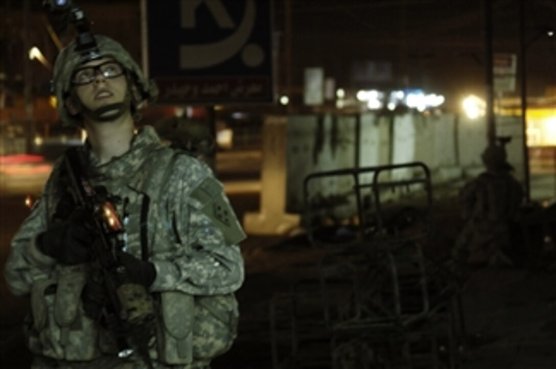 U.S. Army Sgt. 1st Class Brian Ullrich from the 1st Battalion, 68th Armor Regiment, 3rd Brigade Combat Team, 4th Infantry Division scans his area as he provides security outside a Beida neighborhood market shop in Baghdad, Iraq, on Feb. 28, 2008, during an evening dismounted patrol of the area to check on how local businesses are doing.  