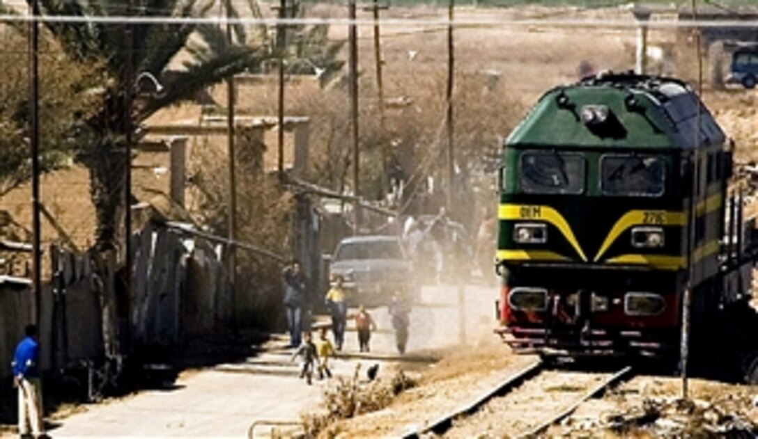 An Iraqi locomotive stirs up the dust as it passes a crowd of villagers upon its approach to the railroad gate to Camp Taji, Iraq March 5, 2008. This is the first time a train has arrived at the coalition installation since the beginning of Operation Iraqi Freedom. 