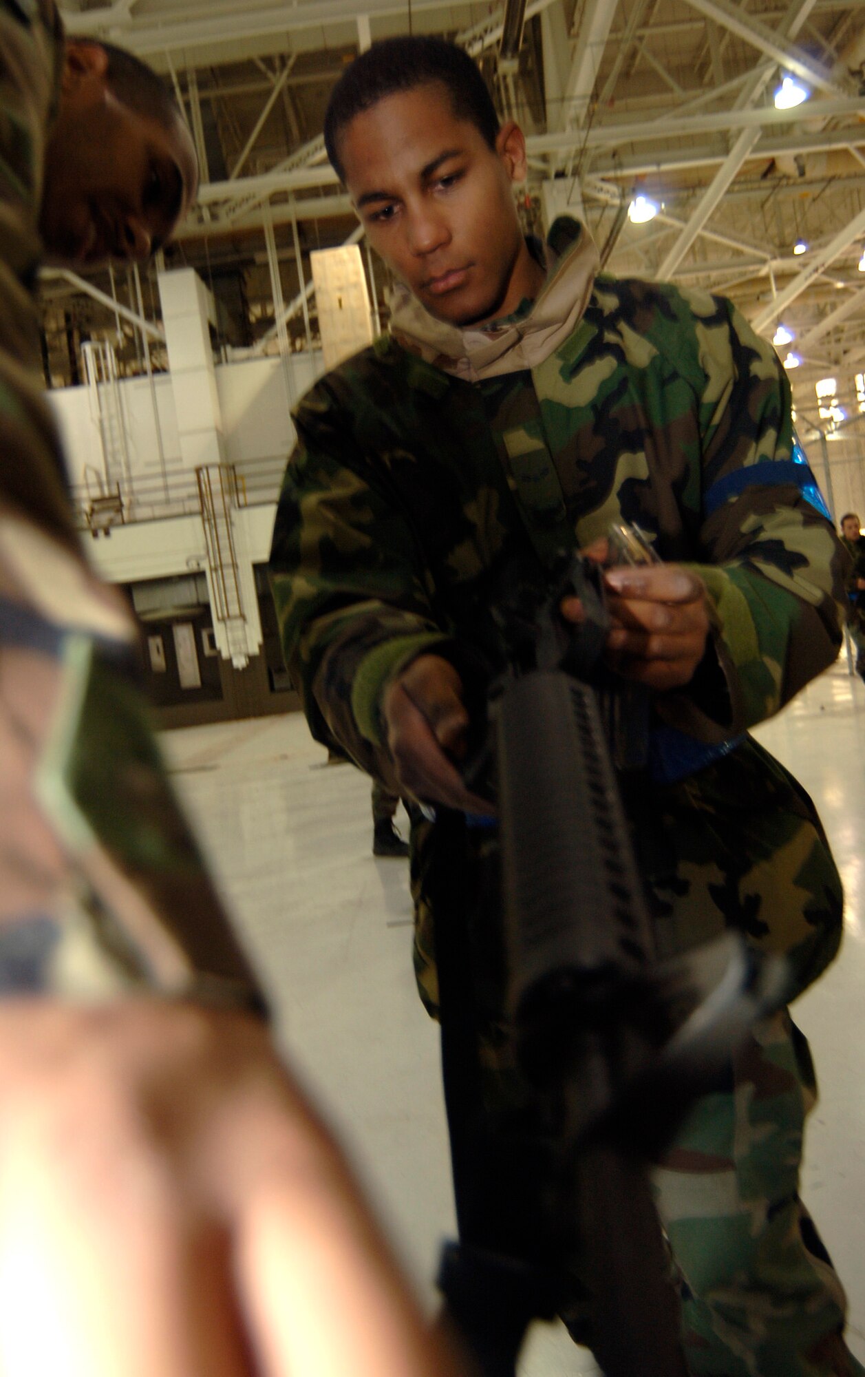 MCCONNELL AIR FORCE BASE, Kan. -- Airman 1st Class, Marlon Woolcock, 22nd Medical Group, places his M-16 rifle into a clearing barrel, while Staff Sgt. Ralph Ortiz, 22nd Logistics Readiness Squadron, instructs for accuracy, March 8, during Ability to Survive and Operate exercise here. Clearing a weapon for safety is just one of the procedures to properly perform a weapons function check. (Photo by Airman 1st Class Maria Ruiz)