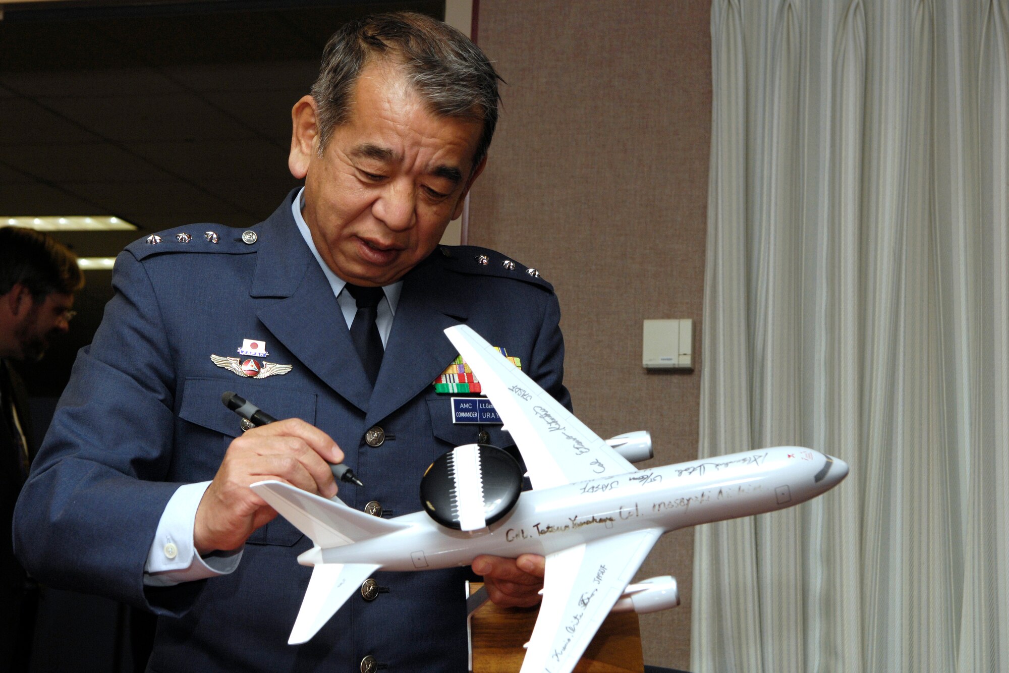 HANSCOM AFB, Mass. -- Lt. Gen. Osahito Urayama, commander of the Japan Air Self Defense Force’s Air Materiel Command, signs a model of the JASDF E-767 Airborne Warning and Control System during his visit to Hanscom March 10. The first of the 767 AWACS jets were delivered to the JASDF nearly a decade ago, and Electronic Systems Center is currently working to upgrade the JASDF E-767 AWACS through the Radar System Improvement Program. (U.S. Air Force photo by Mark Wyatt.)

