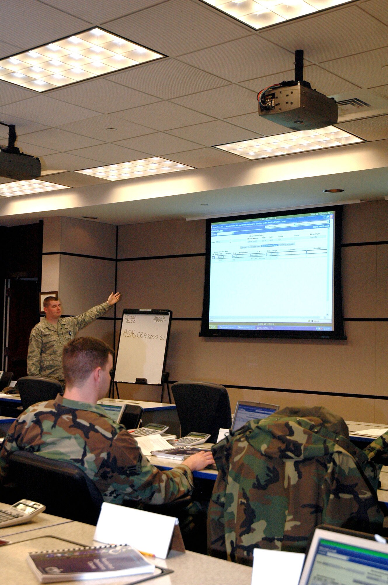 Staff Sgt. Paul Sweeney, an instructor for the U.S. Air Force Expeditionary Center's Aerial Port Operations Course, talks with students Feb. 20 as they work on their computers during course instruction inside the center at Fort Dix, N.J.  The course, taught by instructors in the center's Mobility Operations School Air Transportation Branch, teaches Airmen in the Air Force air transportation career field subject areas such as air freight, passenger service, air terminal operations, and higher headquarters functions. (U.S. Air Force photo/Tech. Sgt. Scott T. Sturkol)
