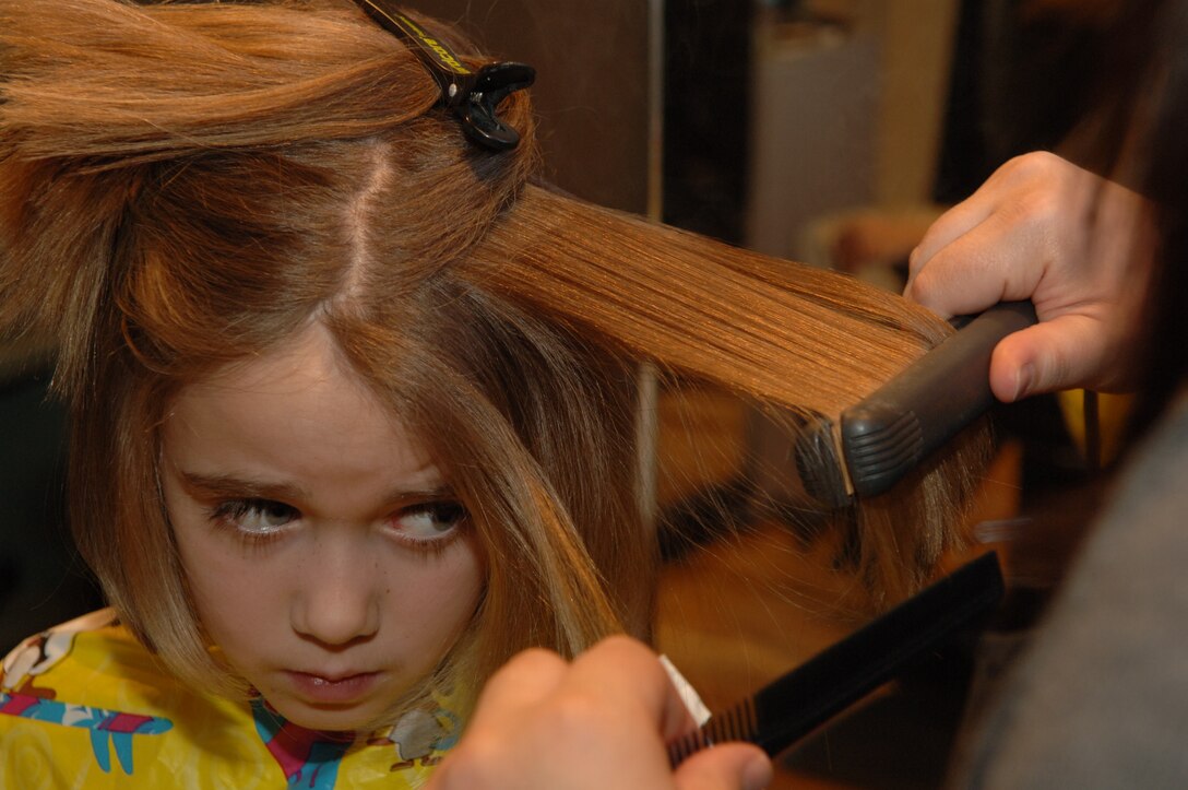 Madeleine Pryor, daughter of Lt. Col. James Pryor, 34th Bomb Squadron commander, has her hair cut to donate to the Locks of Love Organization March 5.  Fourteen 28th Operations Group spouses, three family members and one enlisted Airman volunteered to donate six to 10 inches of hair to Locks of Love, a non-profit organization that provides hair pieces to financially disadvantaged children under the age of 18; a total of 180 inches of hair was donated. (U.S. Air Force Photo/Airman Corey Hook)
