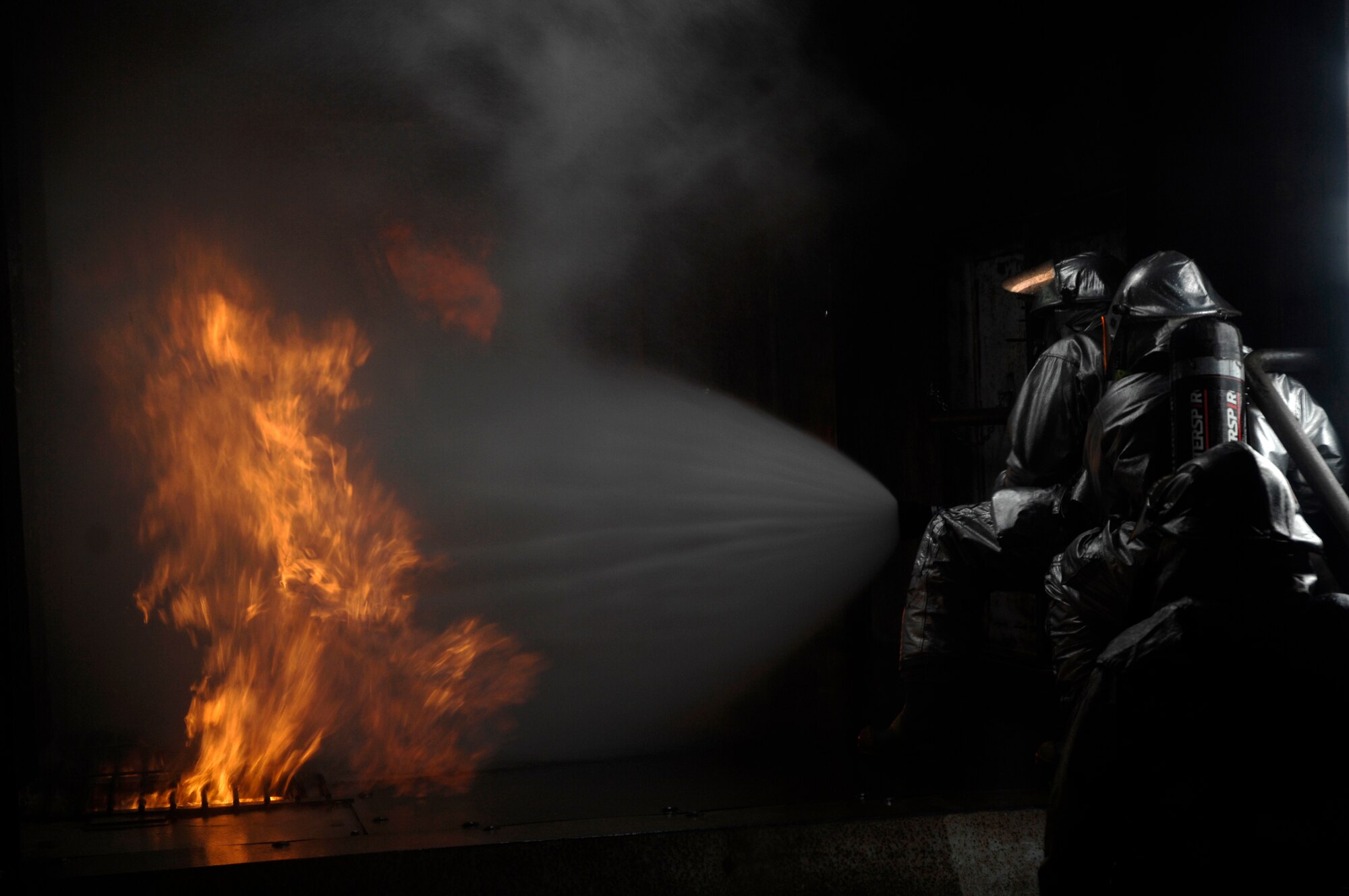 48th Civil Engineer Squadron firefighters extinguish a simulated battery fire inside an aircraft fire trainer, March 8 at RAF Mildenhall, England. Firefighters must train constantly to stay proficient in their aircraft rescue and firefighting skills. (U.S. Air Force photo by Airman Perry Aston)

