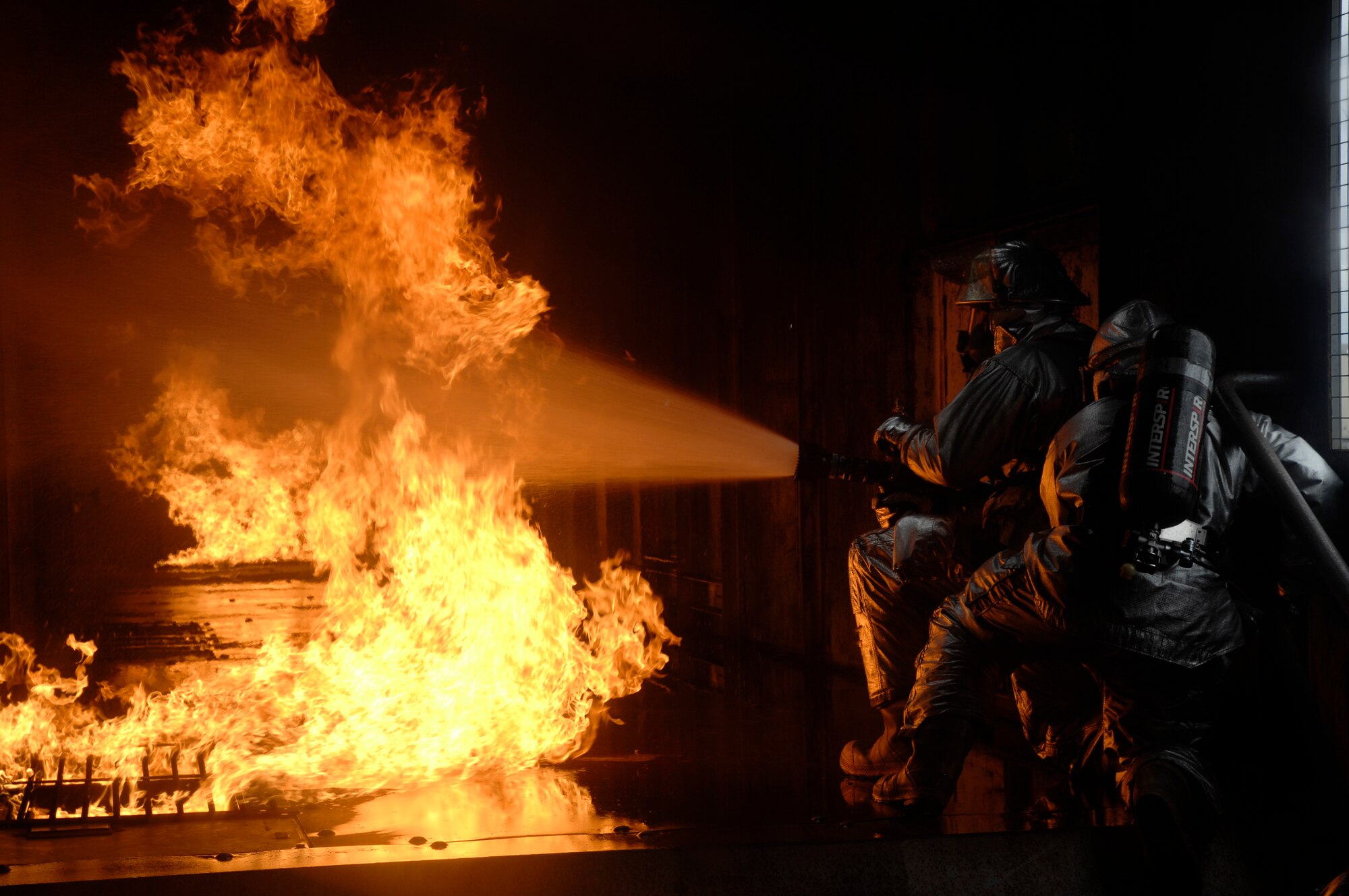 48th Civil Engineer Squadron firefighters extinguish a simulated battery fire inside an aircraft fire trainer, March 8 at RAF Mildenhall, England. Firefighters must train constantly to stay proficient in their aircraft rescue and firefighting skills. (U.S. Air Force photo by Airman Perry Aston)