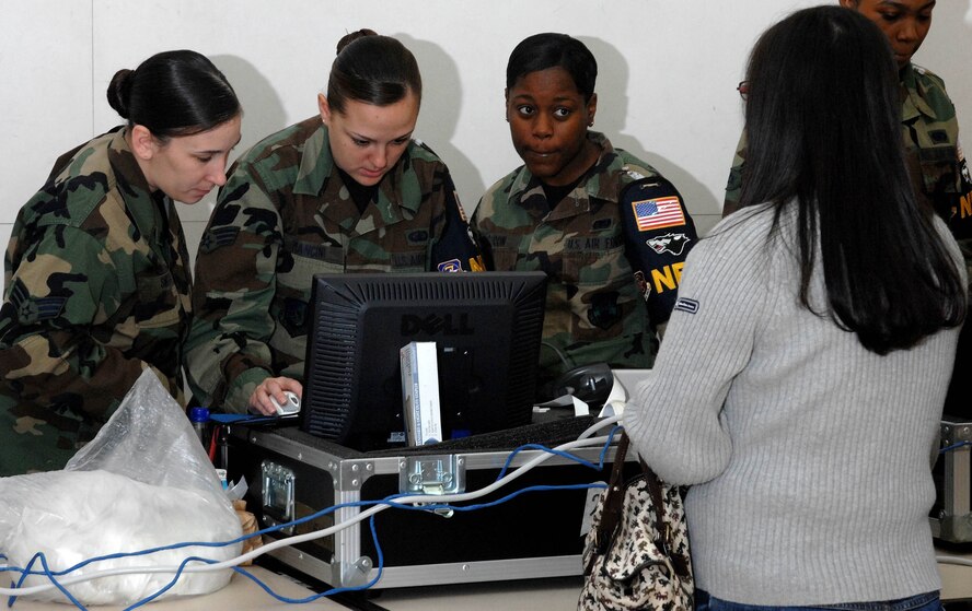 KUNSAN AIR BASE, South Korea -- Senior Airmen Angelique Smith and  Kelli Mancini and Airman 1st Class Lacresha Bacon, noncombatant evacuation operations track system operators, load Mrs. Song Sok's information into a NEO tracking system. March recognizes the accomplishments of women and their remarkable contribution to society. (U.S. Air Force Photo/Senior Airman Steven R. Doty)                                