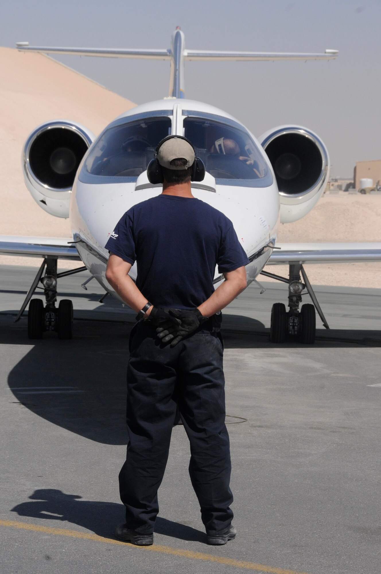 James Dial prepares to marshal a C-21 taking off from a Southwest Asia flightline March 8. The C-21 Lear Jet serves as a distinguished visitor transportation aircraft here and flies throughout the Horn of Africa and Persian Gulf. Mr. Dial is a contracted maintainer deployed from Peterson Air Force Base, Colo. (U.S. Air Force photo/Senior Airman Domonique Simmons)