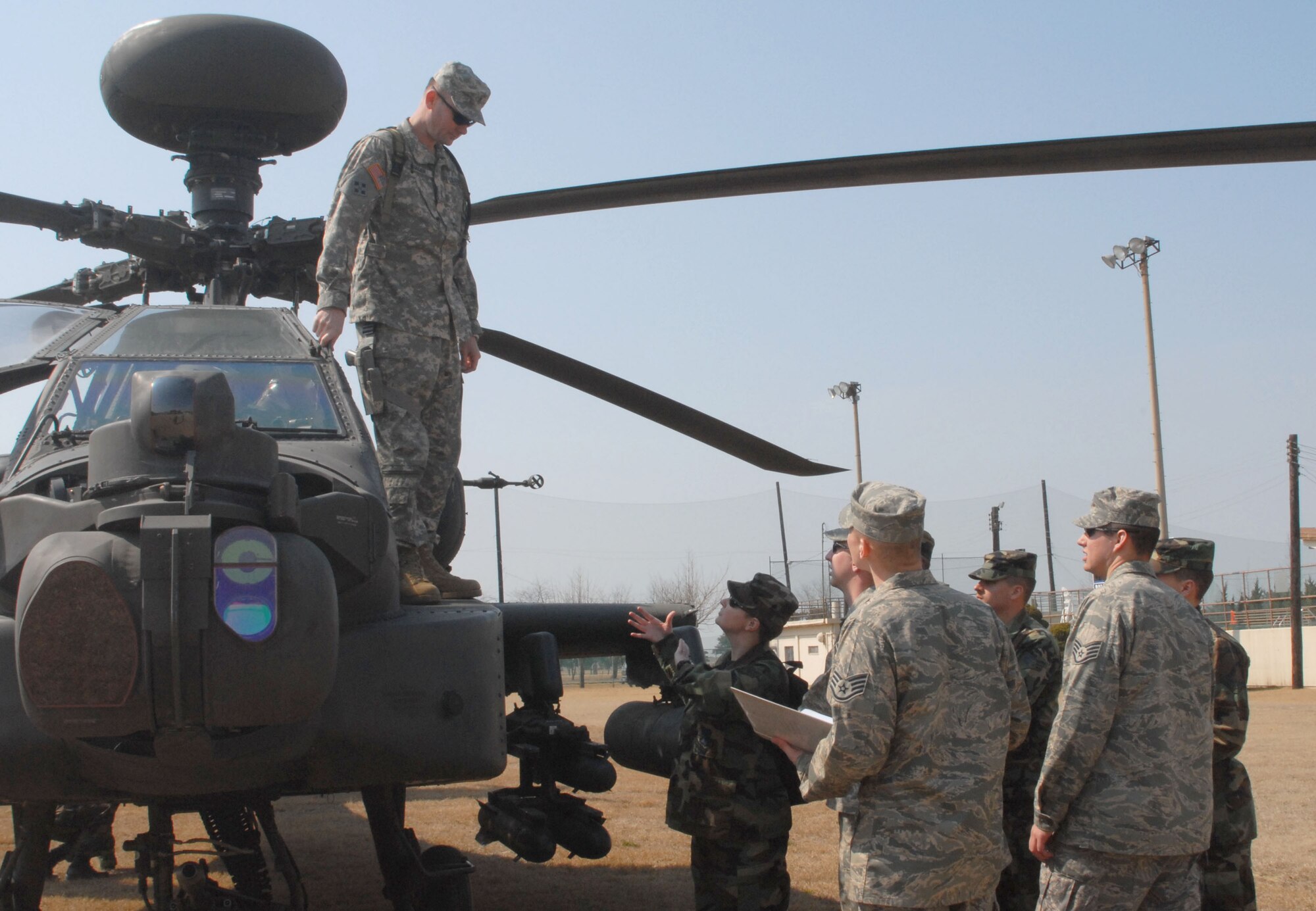 KUNSAN AIR BASE, Republic of Korea -- Chief Warrant Officer 3rd Class Pat Nager, a standardization instructor pilot with Charlie Company, 4-2 Attack Battalion, 2nd Combat Aviation Brigade from Camp Humphreys answers questions about the AH-64D Apache helicopter posed by the 8th Civil Engineer Squadron's Explosive Ordnance Disposal Airmen during a static display of the aircraft here Mar. 10.  The event was designed to inform Airmen about the aircraft and the Army's current mission here.  (U.S. Air Force photo/Staff Sgt. Darcie Ibidapo))