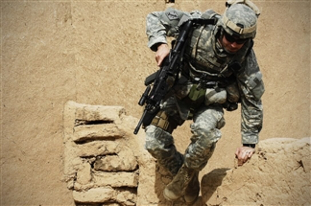 U.S. Army Sgt. Jeremiah Trench scales a wall as he conducts a cordon and search mission with soldiers from 3rd Battalion, 6th Field Artillery, 10th Mountain Division in Kirkuk, Iraq, on March 3, 2008.  Trench is the team chief with 2nd Psychological Operations Group, attached to 10th Mountain Division.  