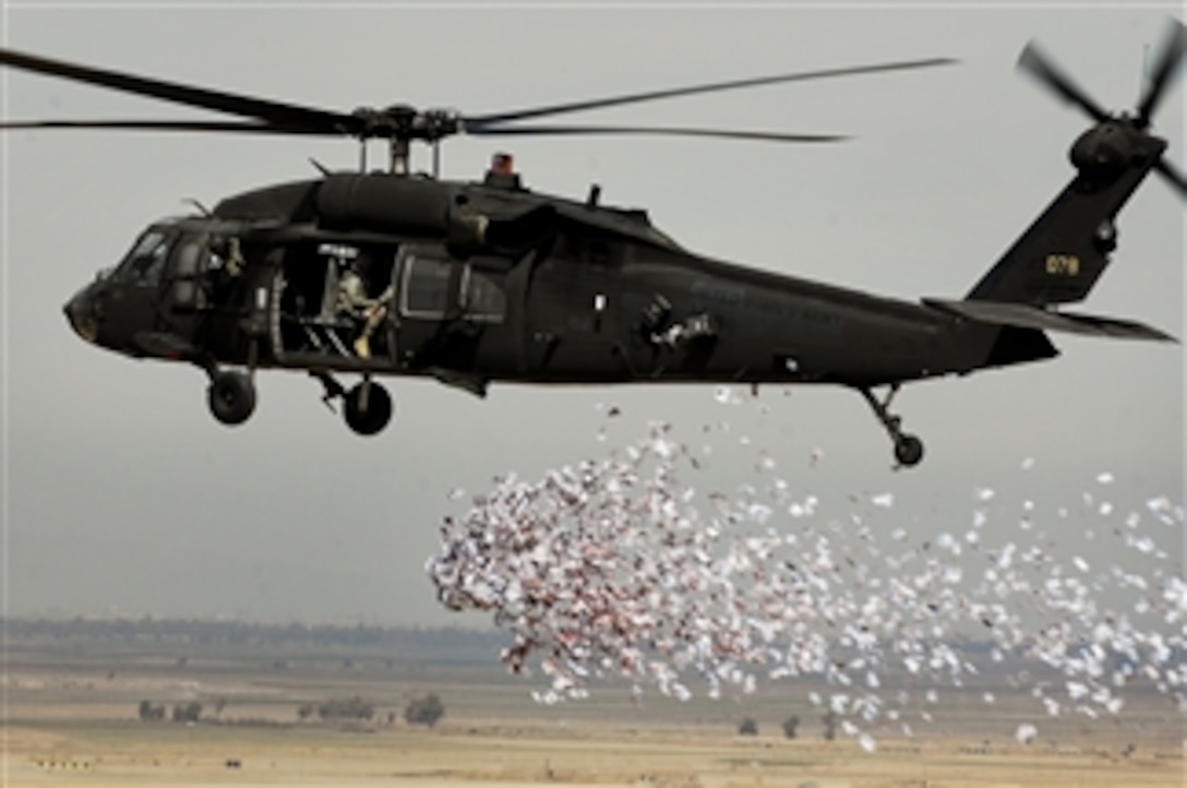Soldiers from the U.S. Army's 350th Tactical Psychological Operations, 10th Mountain Division, drop leaflets over a village near Hawijah in Kirkuk province, Iraq, on March 6, 2008.  The leaflets are intended to promote the idea of self-government to area residents.  