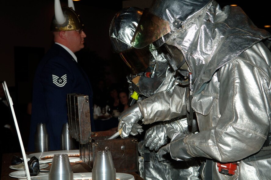 FAIRCHILD AIR FORCE BASE, Wash. –Two firefighters from the 92nd Civil Engineer Squadron put the final ingredient into the grog bowl as Sergeant at Arms Tech. Sgt. Robert Winner, 92nd Security Forces Squadron, looks on during the 92nd Mission Support Group dining out at Club Fairchild March 7. The final ingredient was dry ice, which provided the fog that rose from the grog bowls.(U.S. Air Force photo/Senior Chad Watkins)