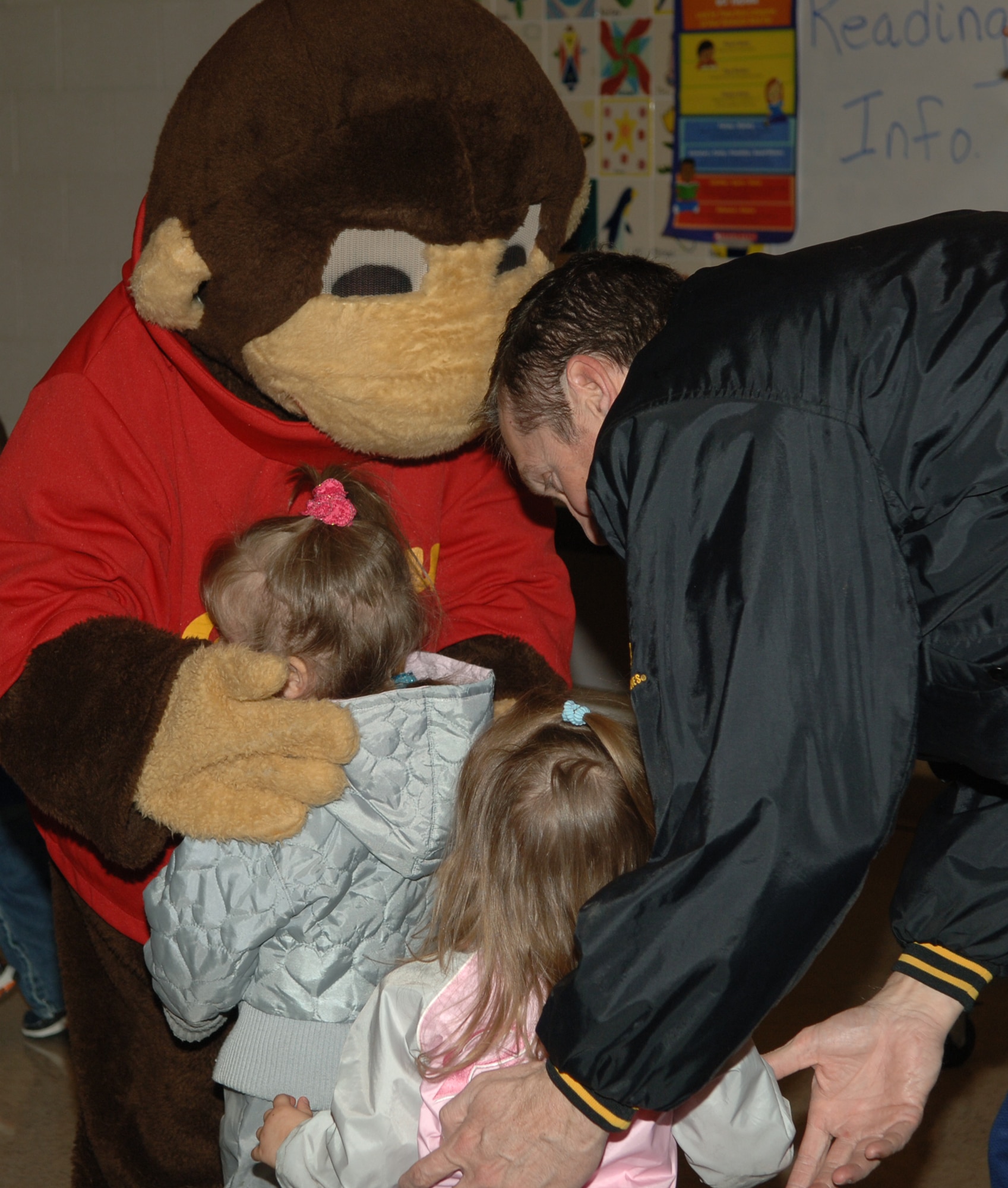 FAIRCHILD AIR FORCE BASE, Wash. – Capt. Peter Sherman, 92nd Air Medical Dental Squadron, encourages his daughter Grace to hug Curious George like her big sister Isabel does. Clifford the Big Red Dog also visited during Family Night at Michael Anderson Elementary March 6. (U.S. Air Force photo/Senior Airman Jocelyn Ford)
