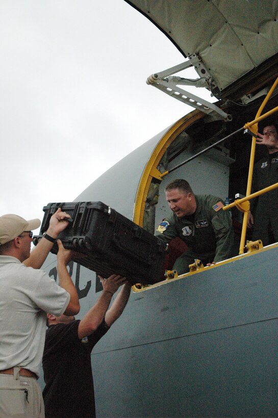 Navy divers hand Master Sgt. Matt Miltz a sealed case containing remains of a B-24 Liberator crewmembers shot down during World War II off the western Pacific island of Palau March 3 at Palau International Airport, Palau. Sergeant Miltz placed the case, and another like it, in the cabin of the KC-135 Stratotanker that flew the remains to Hawaii for identification. Sergeant Miltz is assigned to the 190th Air Refueling Wing from the Kansas Air National Guard. (National Guard Bureau photo/Staff Sgt. W. Michael Houk) 
