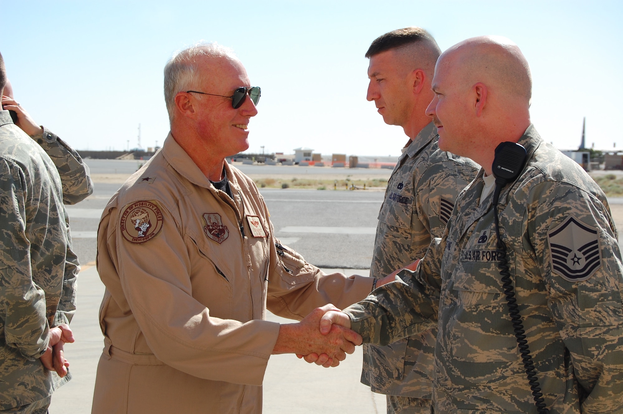 Brig. Gen. Thomas Haynes, U.S. Air Forces Central director of mobility forces, shakes hands with Master Sgt Henry Augustine, deployed from MacDill Air Force Base, Fla., while Tech. Sgt. Michael Edie, deployed from Yokota Air Base, Japan, stands in the background during his March 8, 2008, visit to an air base in the Persian Gulf Region.  The general visited the 386th Air Expeditionary Wing to see first-hand how Airmen support the deployed airlift mission.